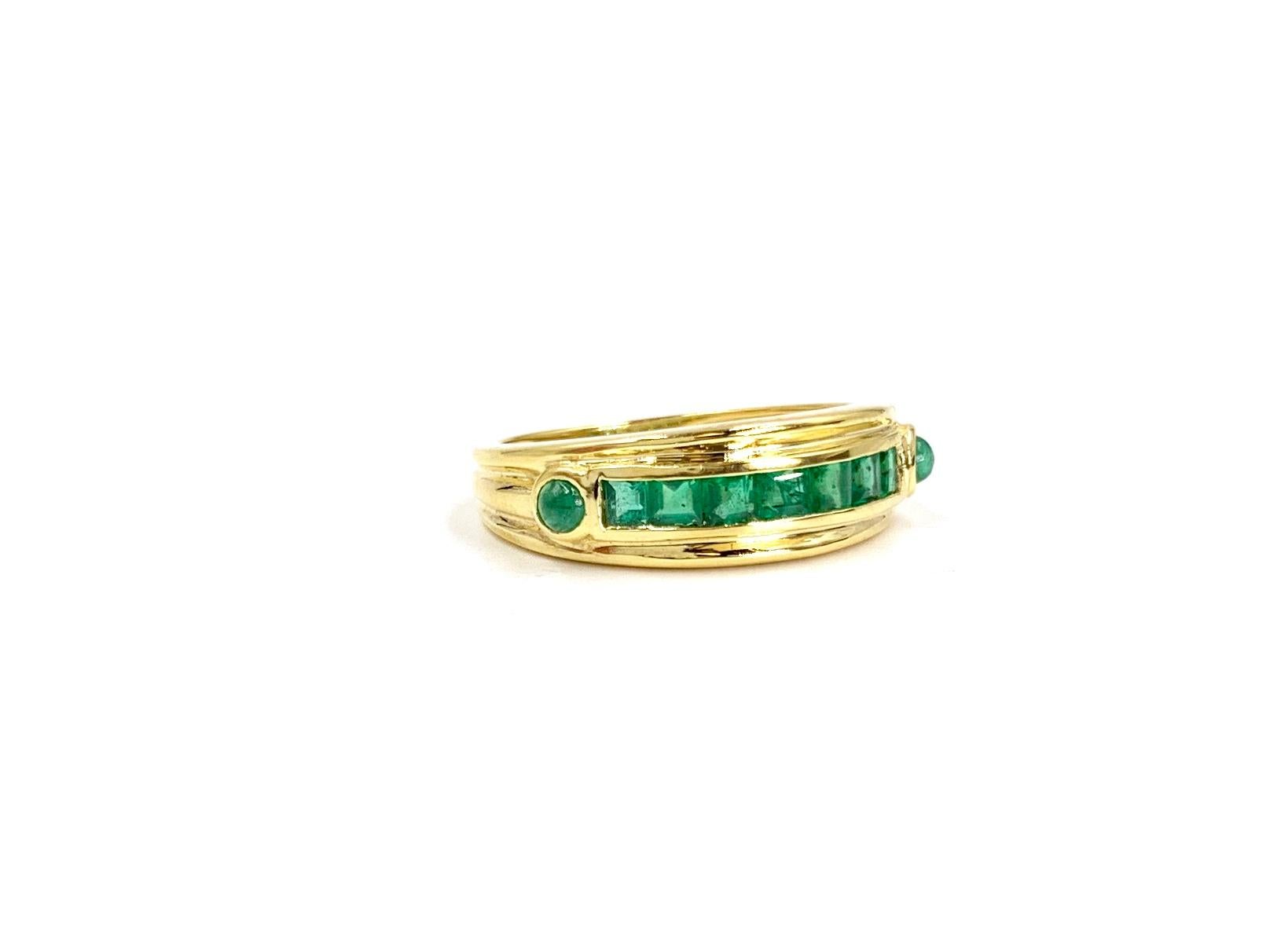 A wearable polished 18 karat yellow gold band style ring featuring a single row of seven channel set princess cut green emeralds flanked by two round cabochon emeralds. Emeralds have an approximate total weight of 1.11 carats and are of high quality