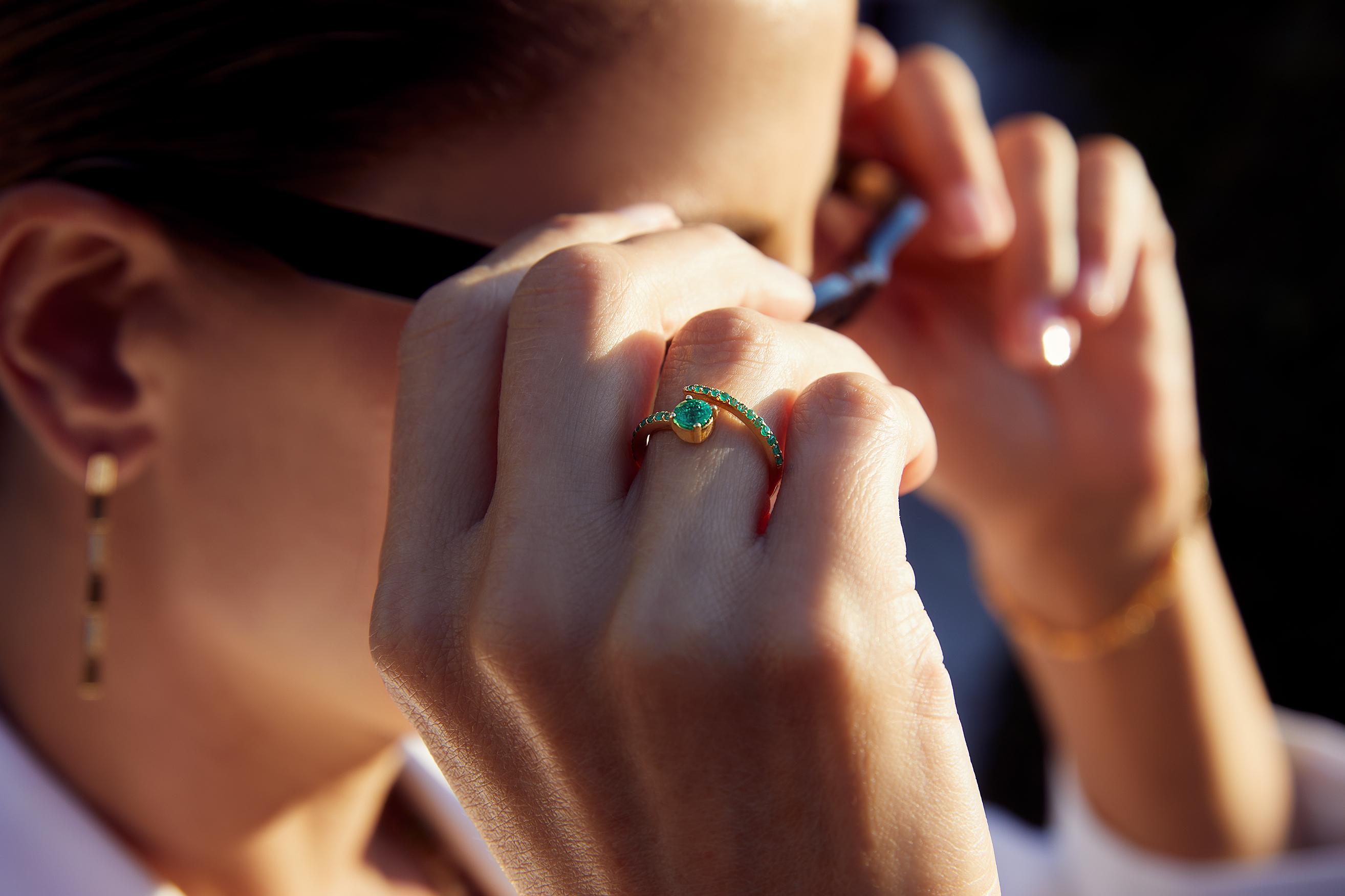 The Grass Seed ring is handcrafted from 18k polished gold and features an Emerald “seed” with a row of smaller pave emeralds set along a grass “sprout”. Inspired by the magic that transpires from the simple act of planting a humble seed, wearing it