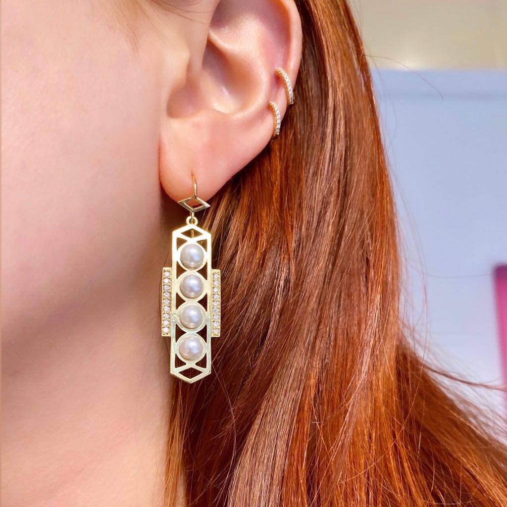 Boucles d'oreilles géométriques en or 18k combinées avec des perles blanches et accentuées par des rangées de diamants.  D'un design moderne, mais avec une influence classique, ils ont été inspirés par le design de la Grèce antique et de l'Art