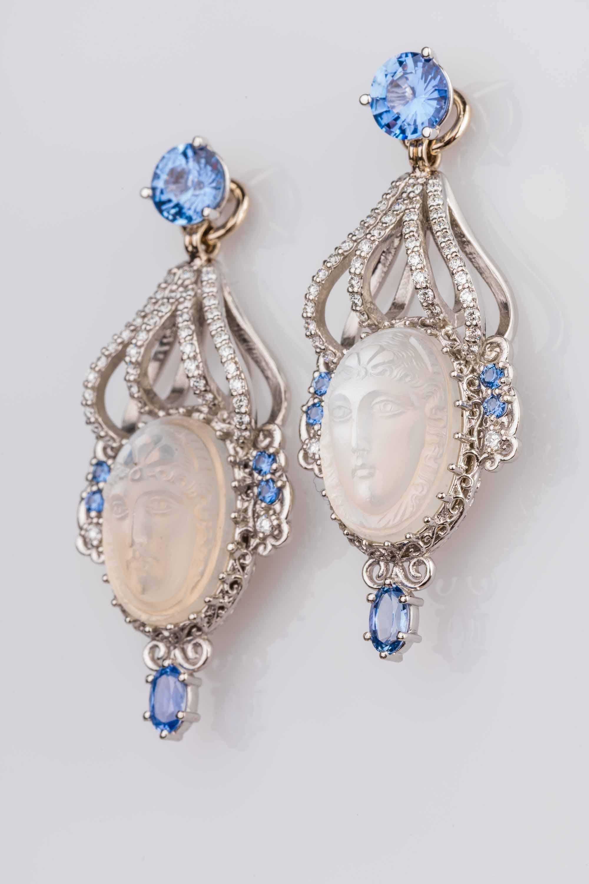 A pair of platinum and 18k white gold earring jackets featuring a pair of oval 16.1mm X 11.25mm vintage carved moonstones, 0.56 total carat weight round full cut white diamonds F color VS clarity 0.27 total carat weight round natural Yogo blue