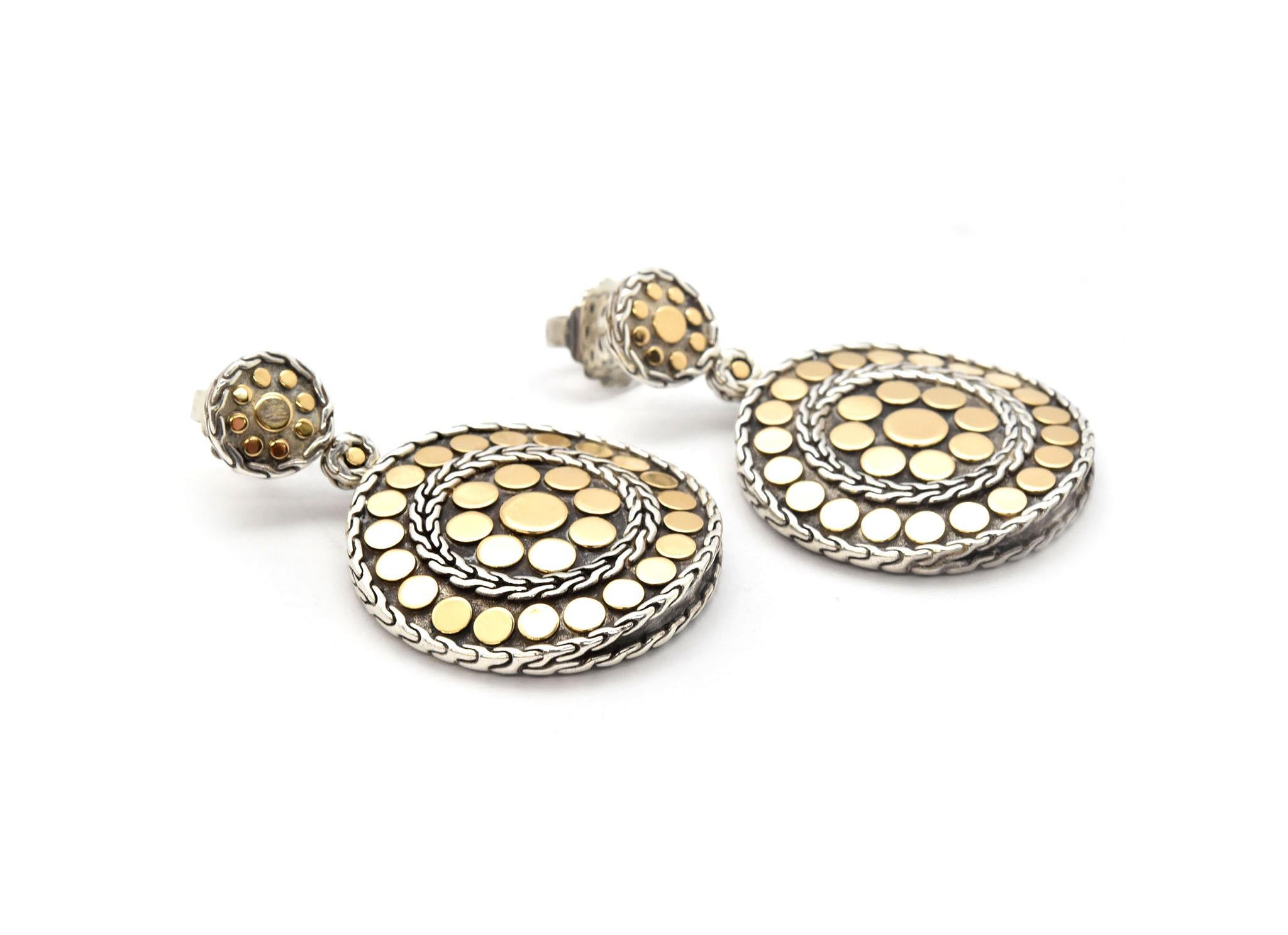 This pair of earrings is made in 18k yellow gold and stainless steel by designer John Hardy in the dot collection. These earrings feature a unique arrangement of gold dot accents and sterling silver designs. The post of the earring sticks into a