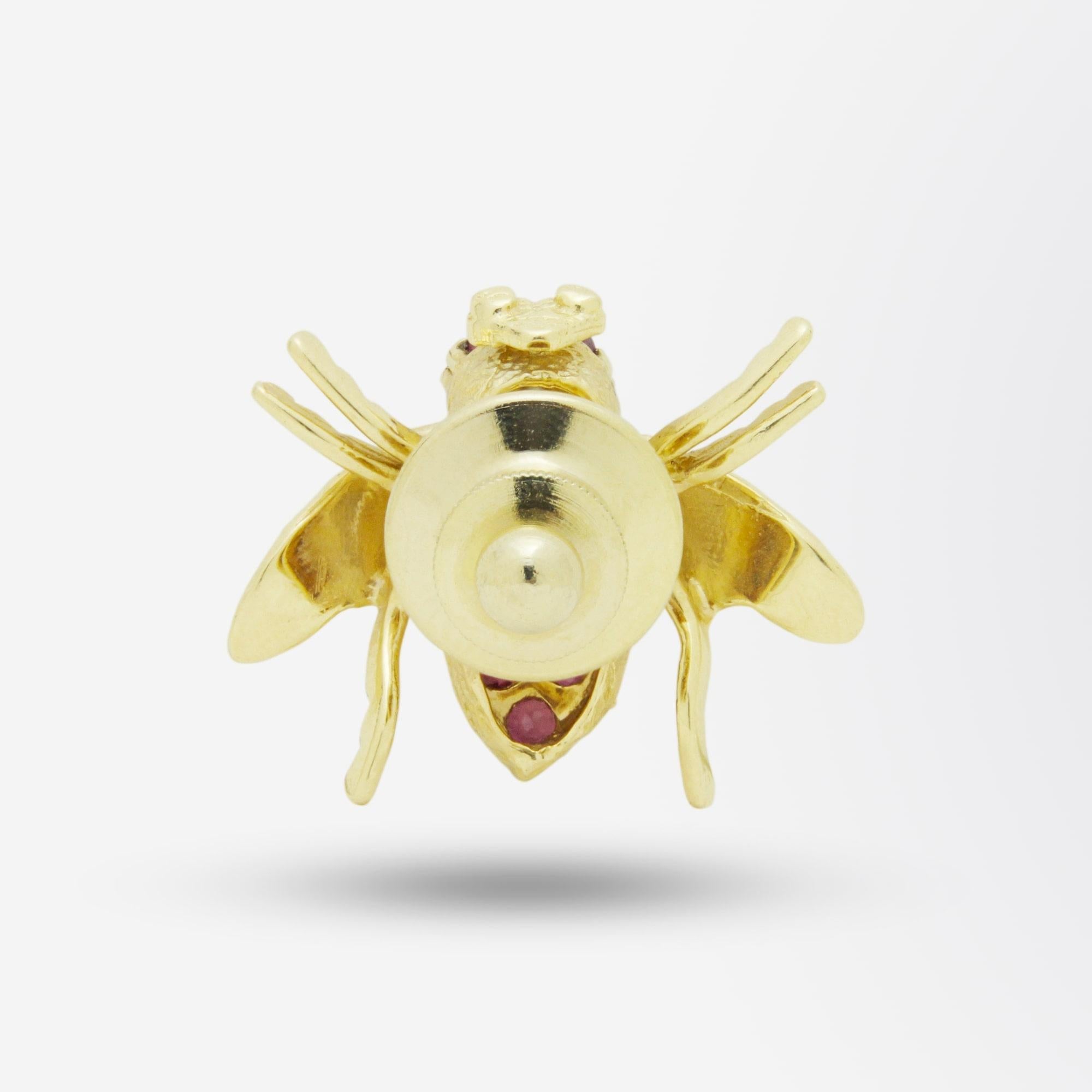 An 18 karat yellow gold pin in the form of a bee. The piece is set with 12 brilliant cut rubies and two natural cultured pearls which form the body of the bee. The rear has a gold plated sprung clip to secure the pin to a garment, which is in good