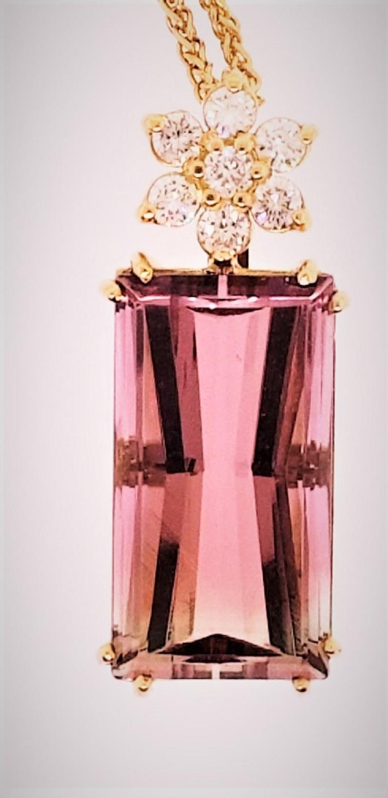 This amazing and brilliant Bi-Color Tourmaline weighing 22.46 carats, sits in an 18 Karat yellow gold basket setting with a diamond flower containing 7 diamonds that weigh 0.59 carats.  The beauty of the stone is not only in the cut, but the fact