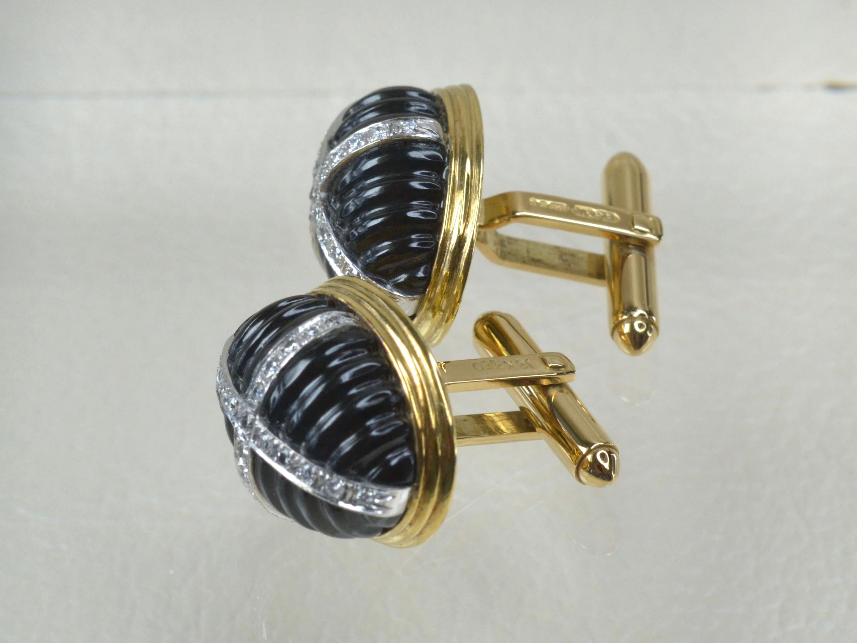18K Gold unisex, statement cufflinks. 
The face of each cufflink features 22mm x 11mm, raised 10mm carved Black Onyx. Each decorated with a cross of twenety-one white Diamonds, set with 4-grains in White Gold. 
The cufflinks feature a combination of