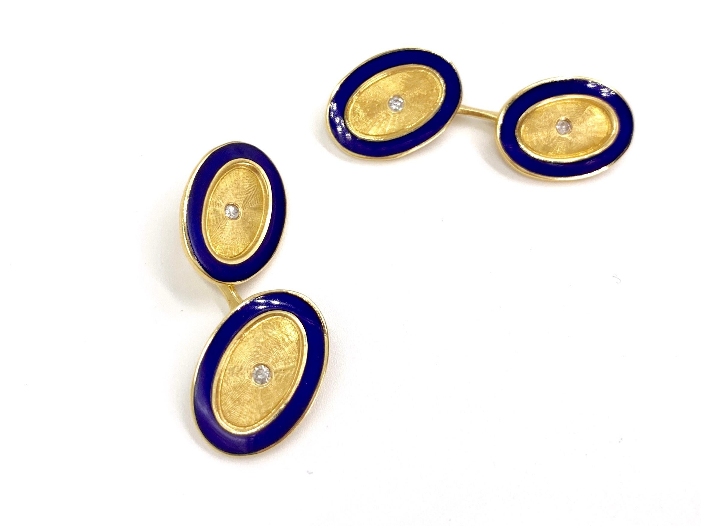 Circa 1970, these classic 18 karat yellow gold oval cuff links feature a vivid cobalt blue enamel edge, hand engraved etching and an understated single bezel burnished round diamond in the center of each link. Links are stamped 750. Front of cuff