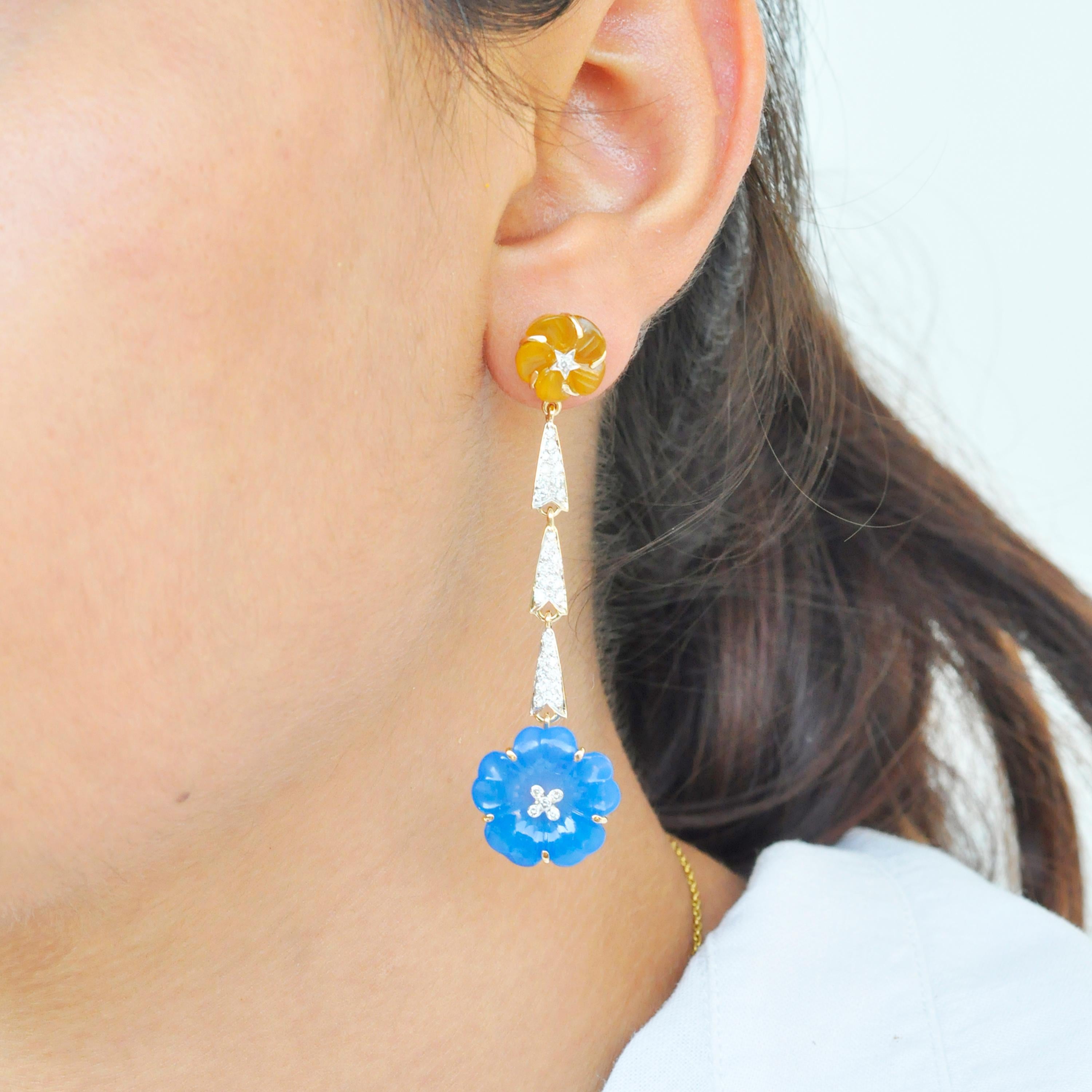 Looking for something chic and completely different? These dangler earrings feature hand carved blue and yellow chalcedony flowers on bottom and top respectively. Joining these two flowers are three streaks of pave set diamonds, set in 18K gold. The