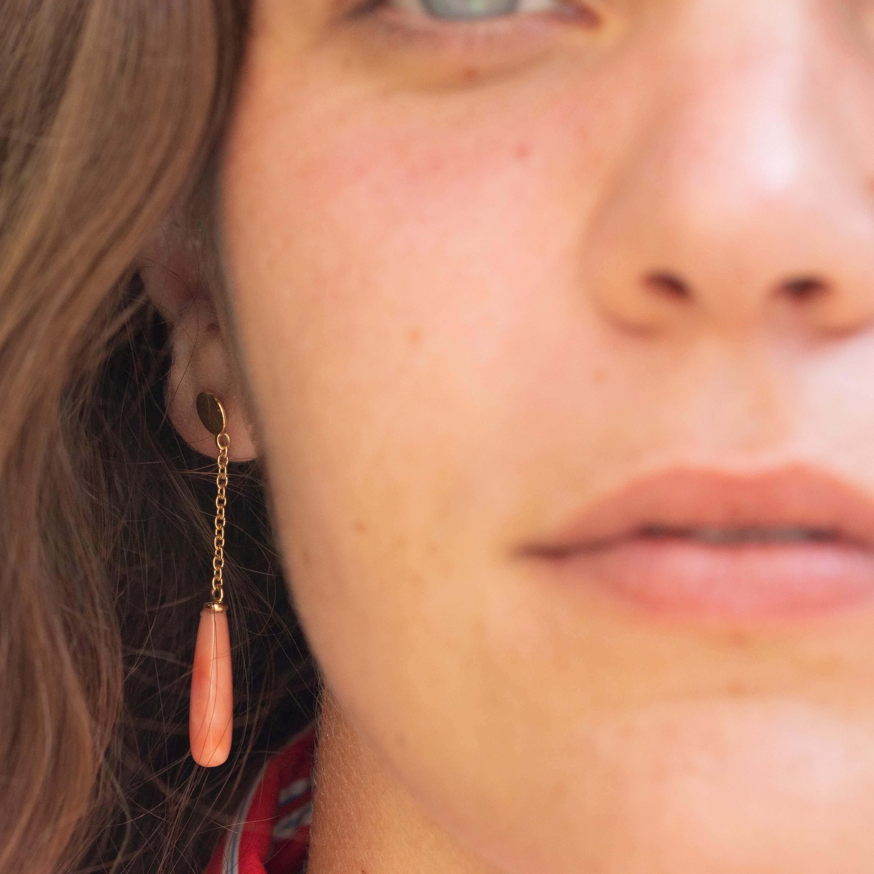 Exotic earrings design. The 18 karat yellow gold enhances the piece with a round circle that is connected to a delicate chain holding a beautifully carved and light pink natural coral long bold tear gem. Italians own the art of coral carving. For