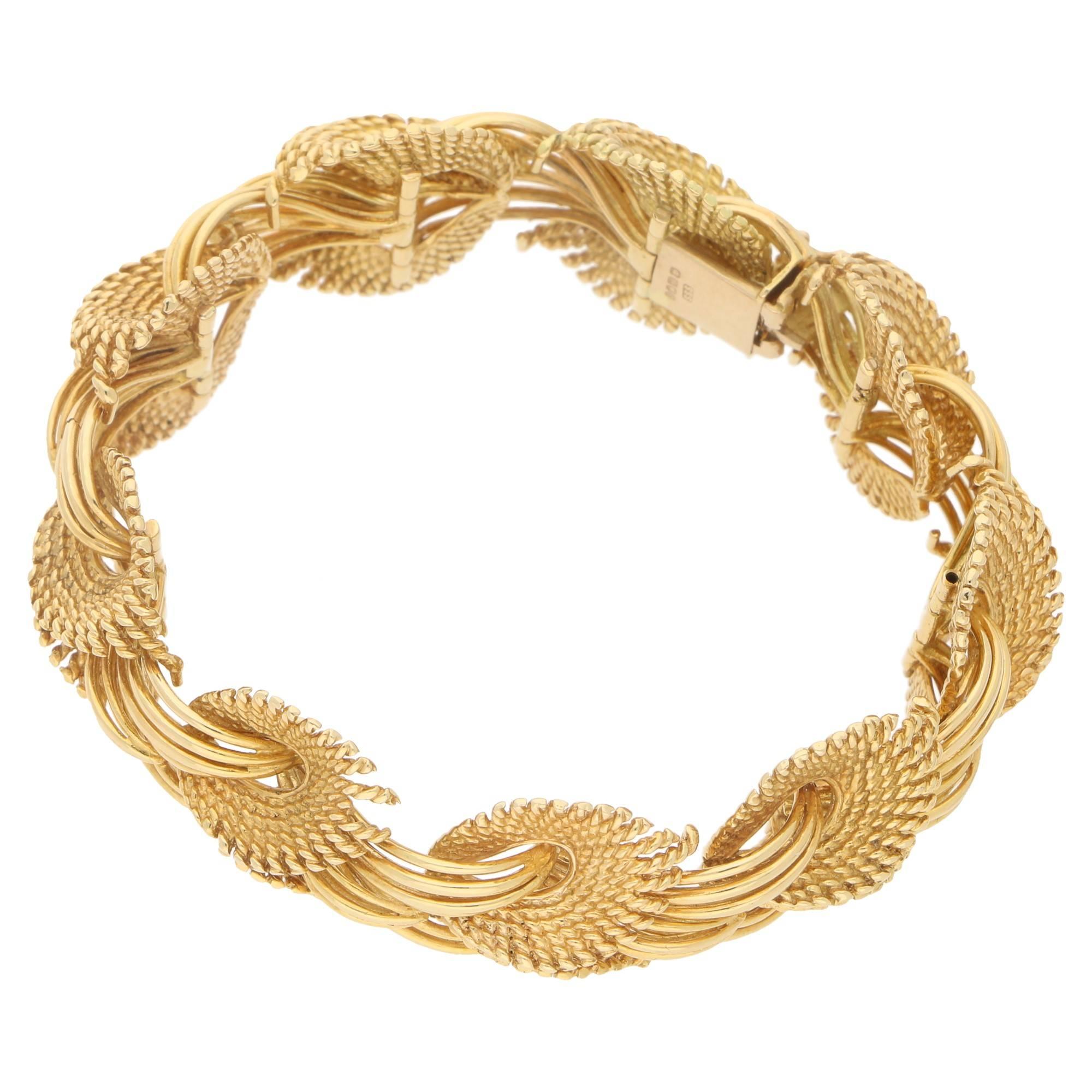A solid 18 carat yellow gold cuff bracelet. The bracelet is formed of stylised leaf motifs in textured gold, with highly polished gold wire. The bracelet is fitted with a subtle tongue piece clasp keeping the pattern fluid when worn. Measures 6.5
