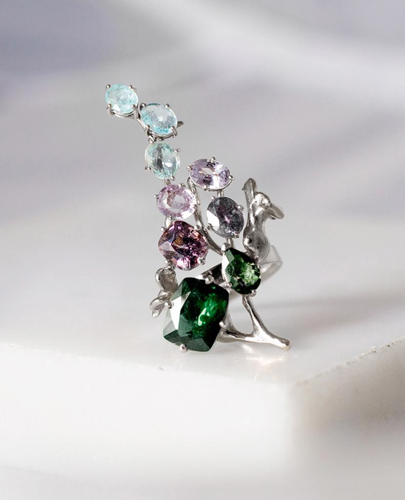 This 18 karat white gold contemporary cocktail ring is an art object with its unusual form. It is encrusted with 12 carats of rose and green sapphires, Paraiba tourmalines, and spinel.

The workmanship is precise, and the piece sparkles as the