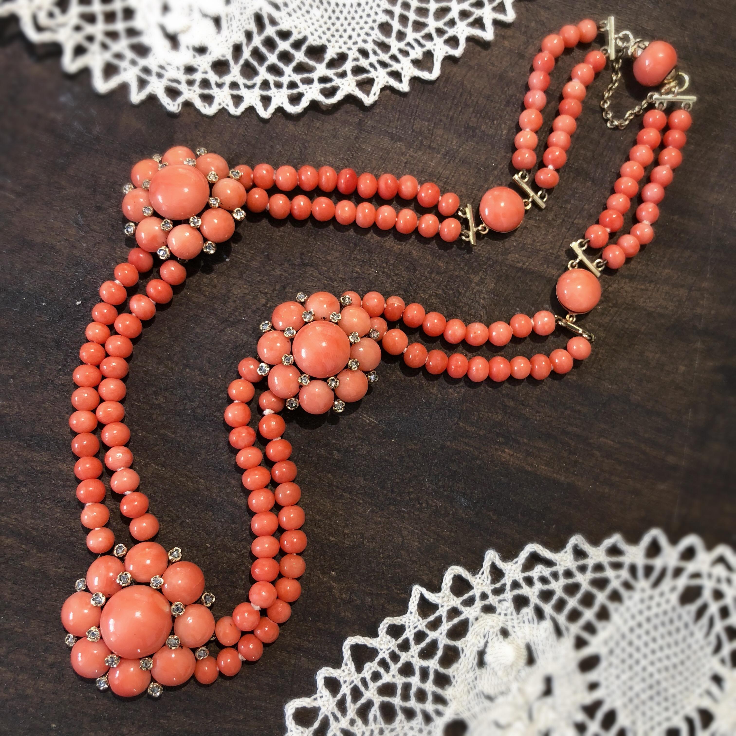 A coral and diamond necklace. Designed as a series of circular coral cabochon and rose-cut diamond floral clusters, with 18ct setting, to the coral bead double row chain with circular coral cabochon spacers. French assay marks. Length 40cms. Weight