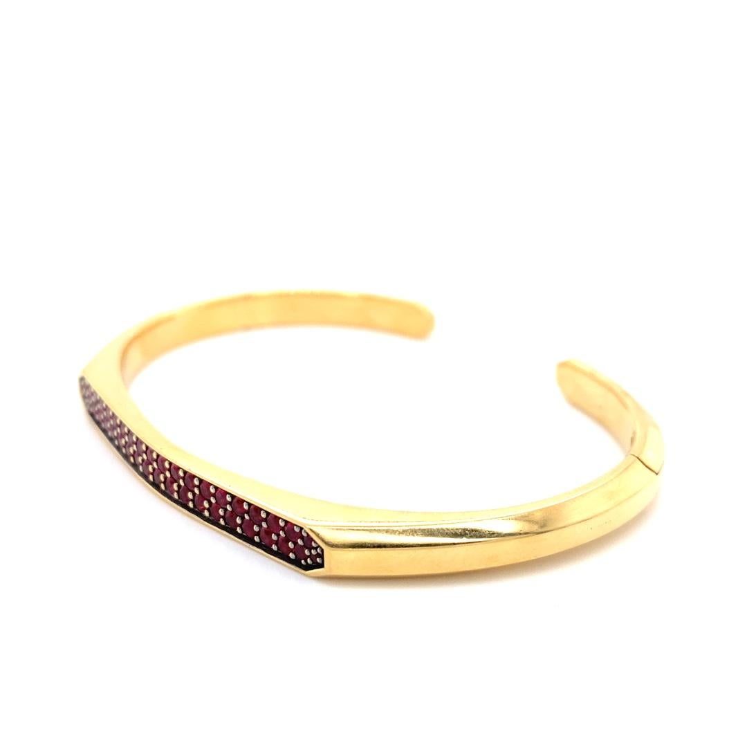 This is a beautiful 18 karat gold cuff bracelet created by David Yurman. The ruby stones add a beautiful and rich red color to the bracelet. This stunning piece is something you won't want to miss. The hinge clasp makes it incredibly easy to wear