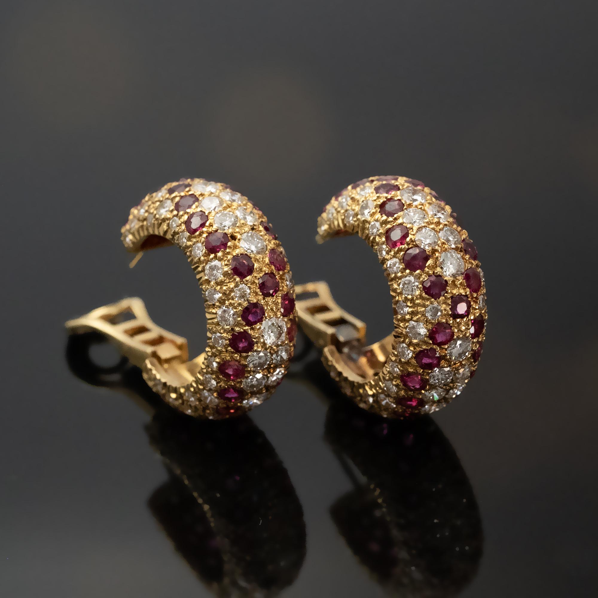 Un paio di raffinati orecchini realizzati in oro giallo a 18 carati, con file alternate di diamanti bianchi e rubini. Il design arrotondato e leggermente bombato esalta la profondità e la luminosità delle gemme, mostrando un preciso equilibrio tra