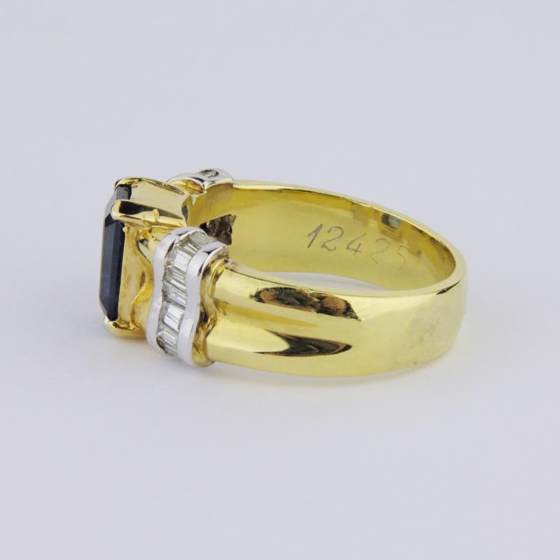 Ein feiner zweifarbiger Ring aus 18 Karat Gold, besetzt mit Diamanten und einem Saphir. Die Schultern des Rings sind mit Kanälen aus Diamanten im Baguetteschliff in Weißgold besetzt, während der zentrale Saphir im Smaragdschliff in Gelbgoldkrallen
