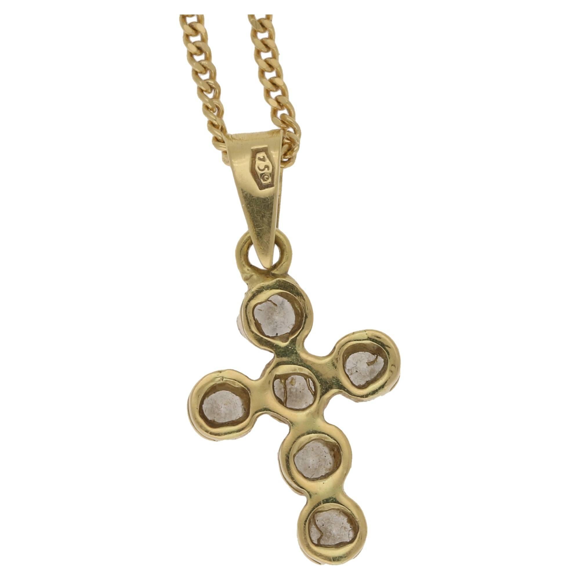 A diamond set cross pendant in 18 carat yellow gold. The cross is formed of six round brilliant cut diamonds tension set in 18 carat yellow gold/ the cross is attached to a pendant bail, affixed to an 18 carat yellow gold curb link chain. Estimated
