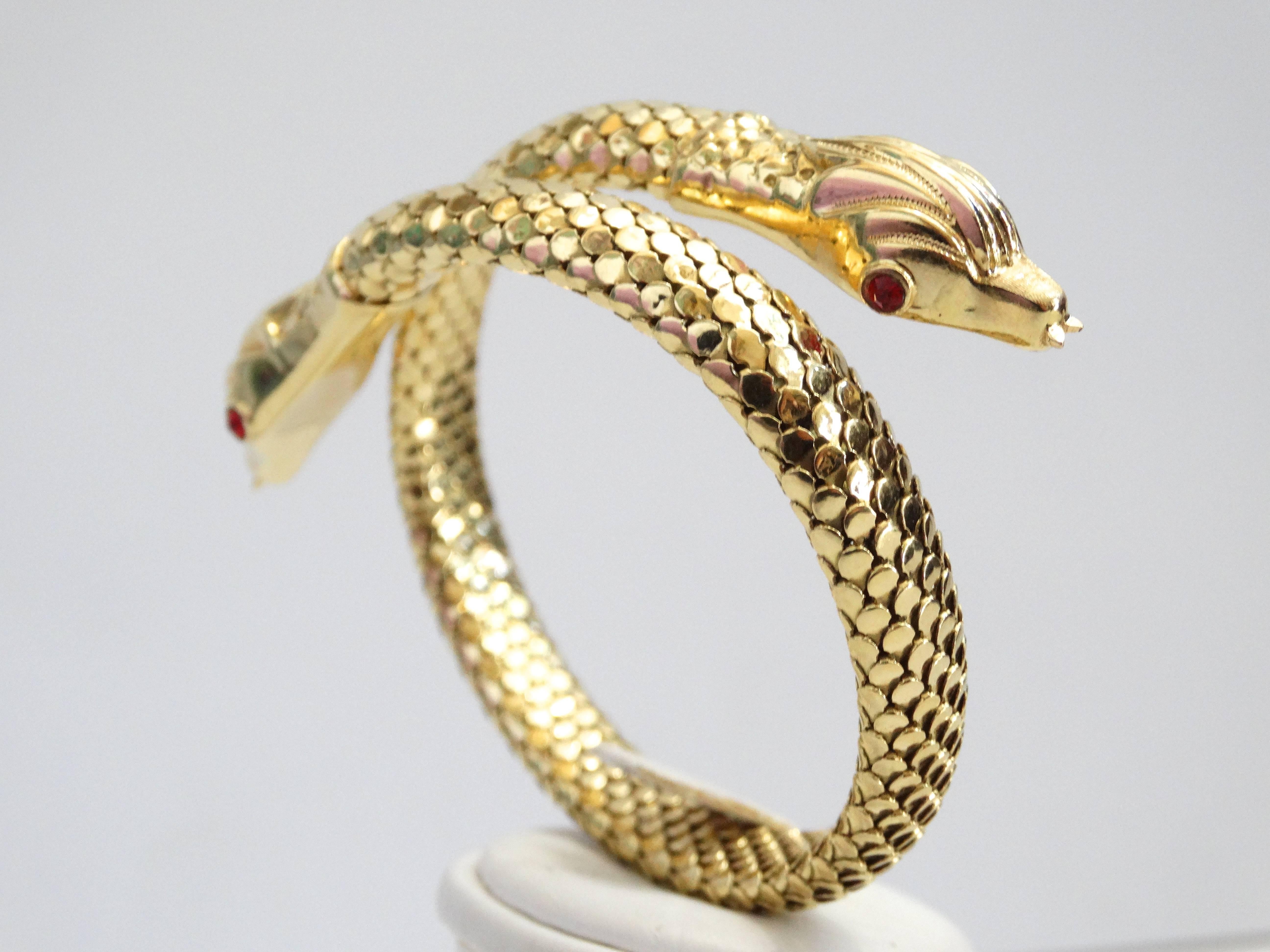 A beautiful and unusual snake bracelet from the mid-century era. Crafted in 18 karat yellow gold, a double serpent body which coils one time around the wrist. The body is textured with small gold plaques piece together to represent scales ( if you