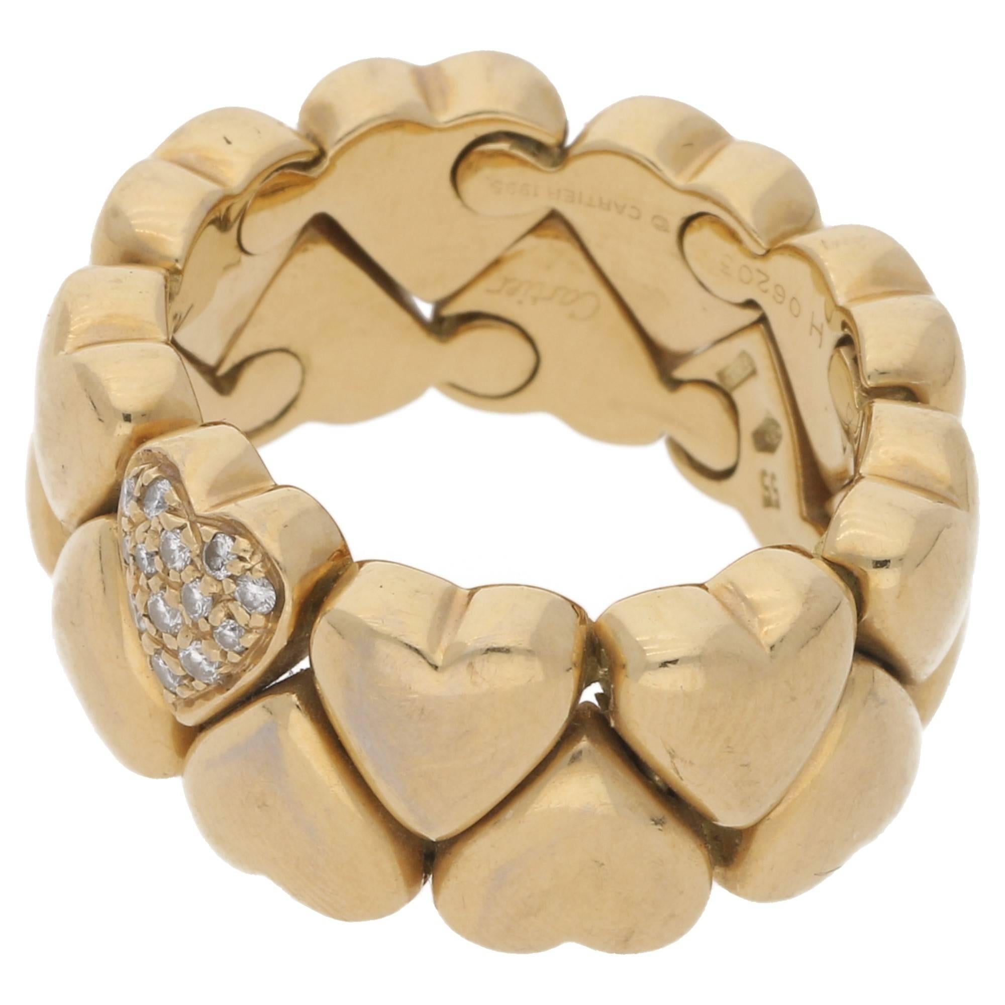 A 1980s Cartier double row heart motif ring in 18ct yellow gold. Each heart is individually linked to the other ensuring a beautiful and tactile flexibility to the ring. One heart is pavé set with thirteen round faceted diamonds with a total carat