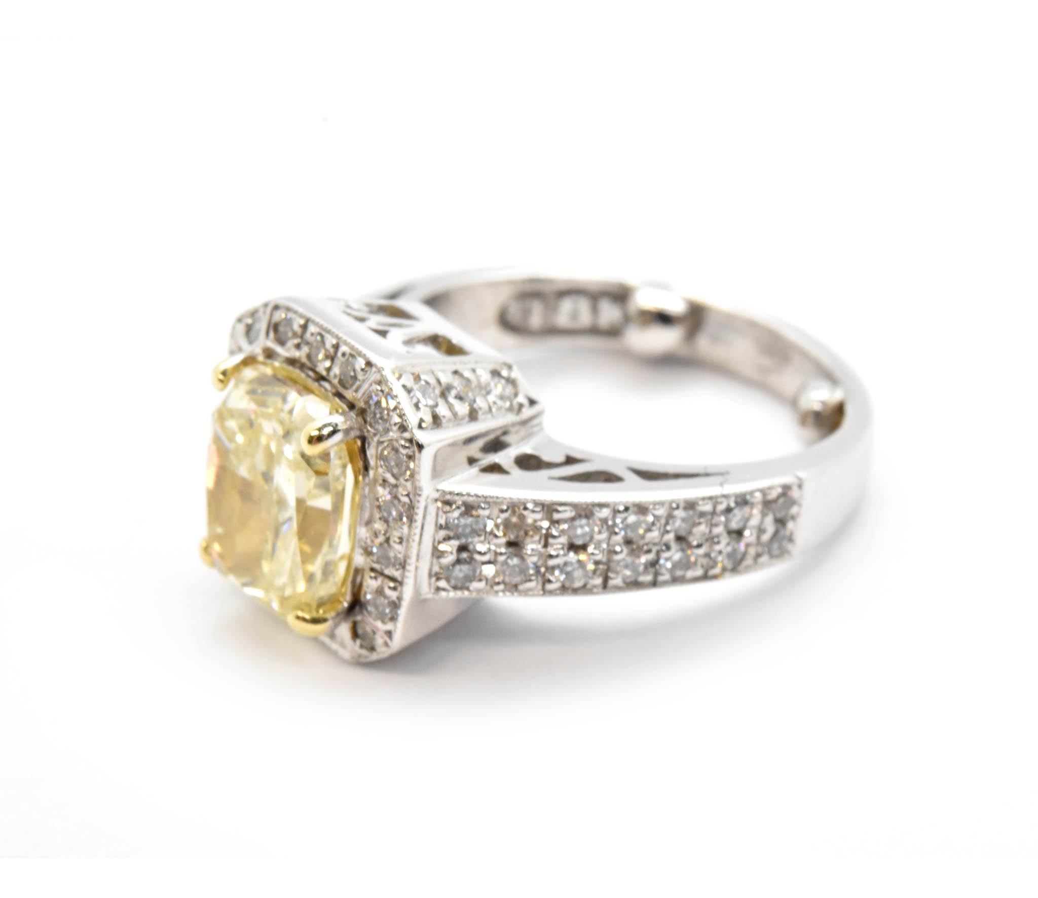 The light fancy yellow cushion cut diamond in this engagement ring is truly a stunning one-of-a-kind at 2.14ct and SI2 in clarity. The mounting of this engagement ring is designed in 18k white gold with 58 round brilliant diamond melee set in the