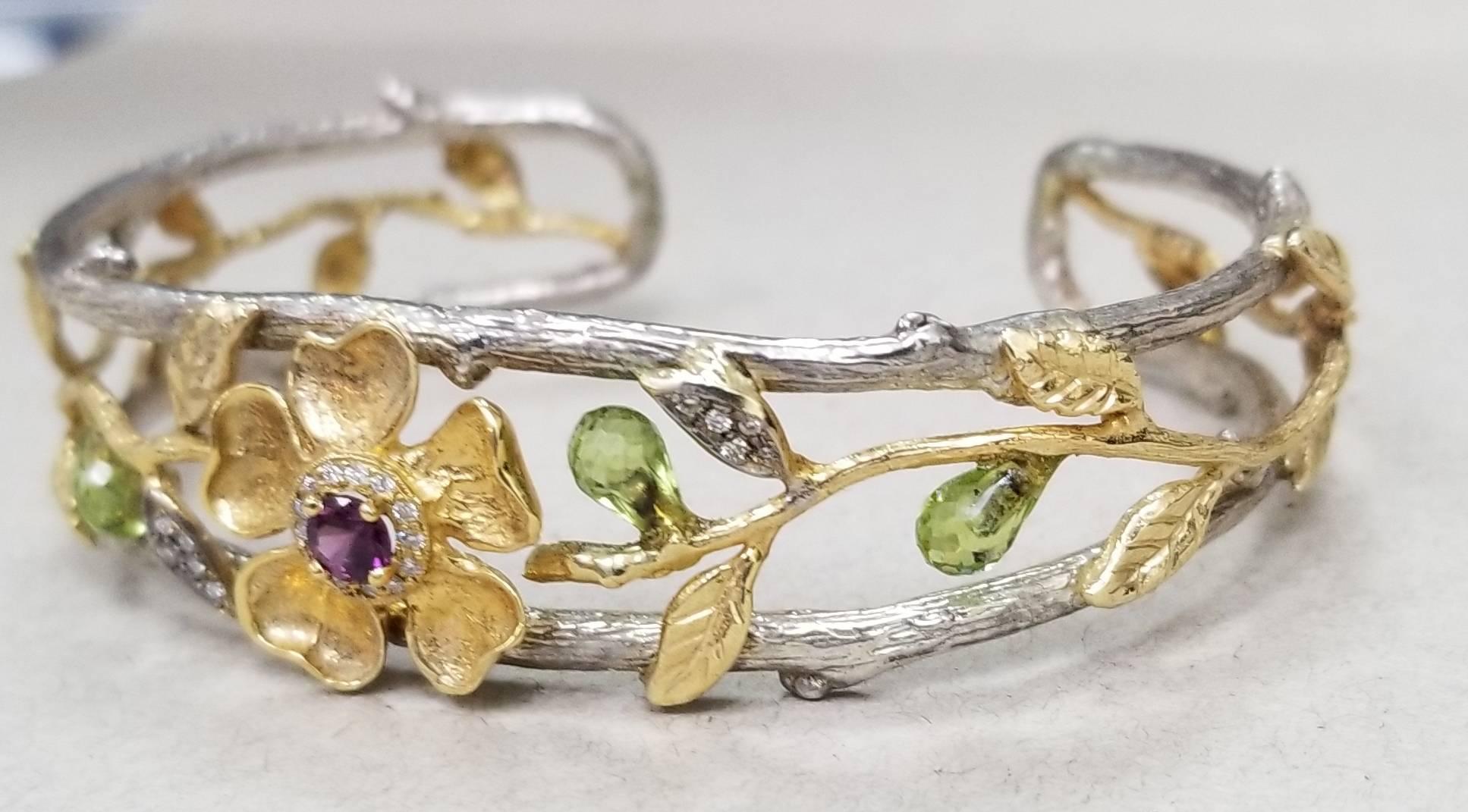 18k yellow gold flower and vine, with 1 round pink tourmaline weighing .33pts. and 23 round diamonds weighing .20pts, accented by 3 tear drop briolette cut peridot weighing 2.25cts.   The 