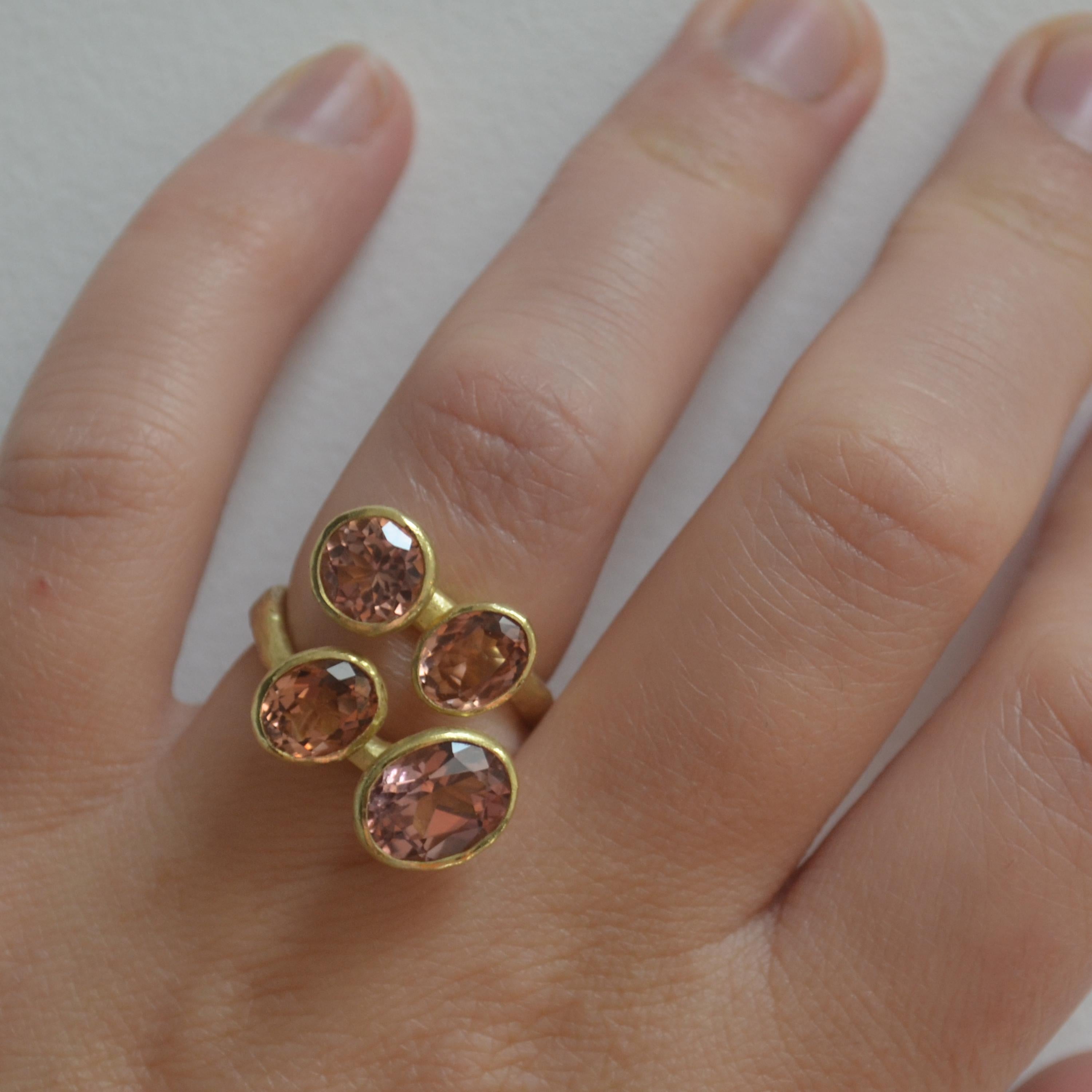 18k gold handmade textured cocktail ring with four pink tourmalines. The largest oval tourmaline is a beautiful rose hue while the surrounding three tourmalines have warm peach tones. Faceted for maximum sparkle and placed to all face upwards to