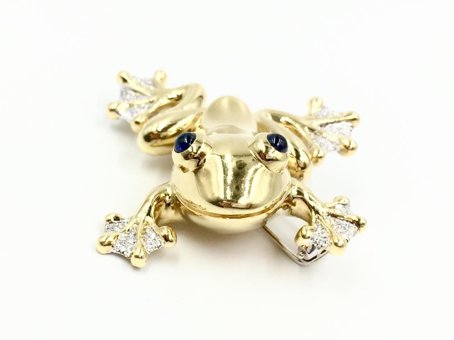 A substantial and well made 18 karat gold frog brooch with three dimensional design. Frog has a lot of character with a smiling face and round cabochon vivid blue sapphires eyes. Approximately 1.02 carats of diamonds are set on the toes in white