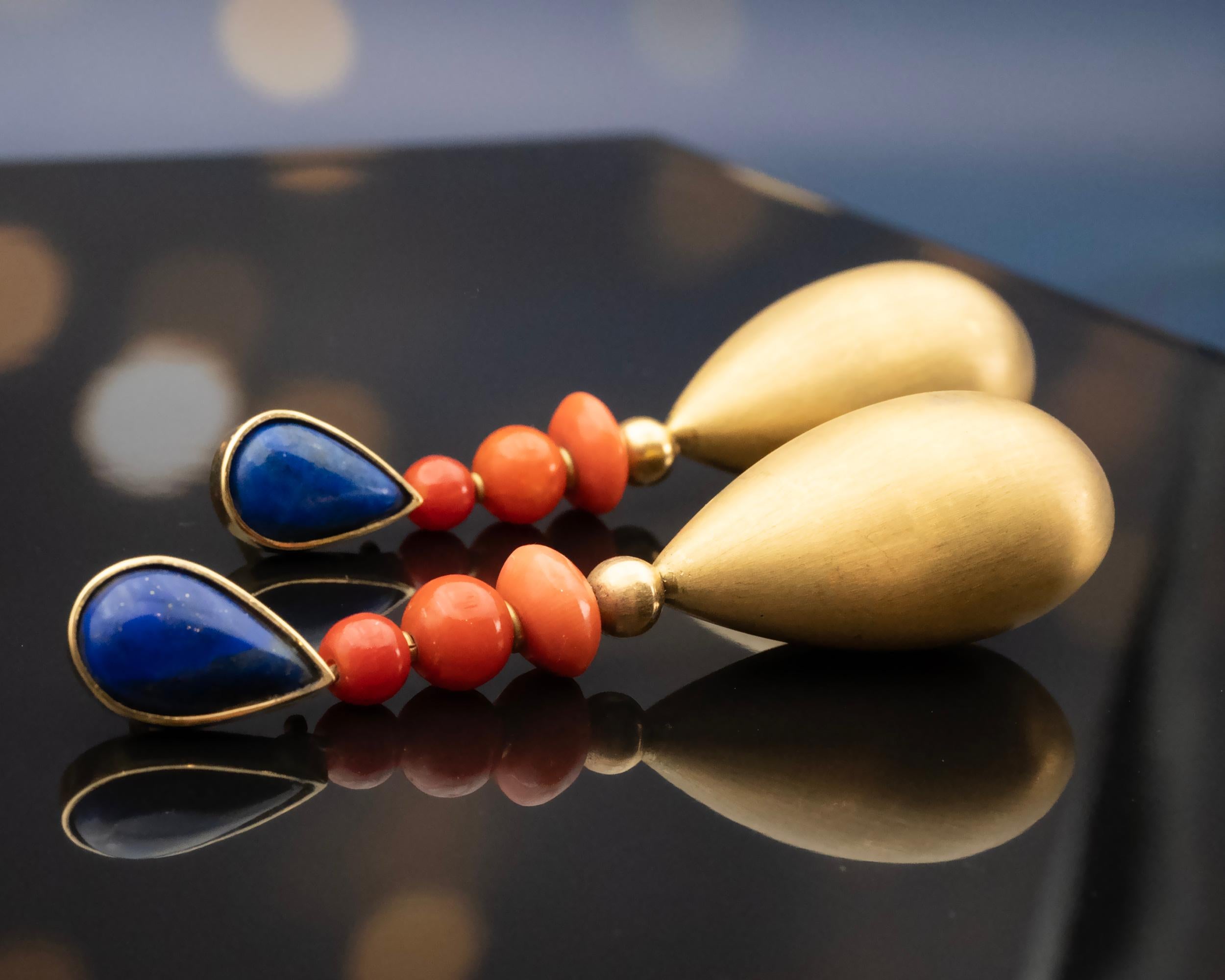 Introducing these stunning 18 karat yellow gold earrings. Meticulously handcrafted, each earring features a pear-shaped lapis lazuli on the lobe, complemented by three dangling coral beads in a subtle gradient of colours. The design takes a modern