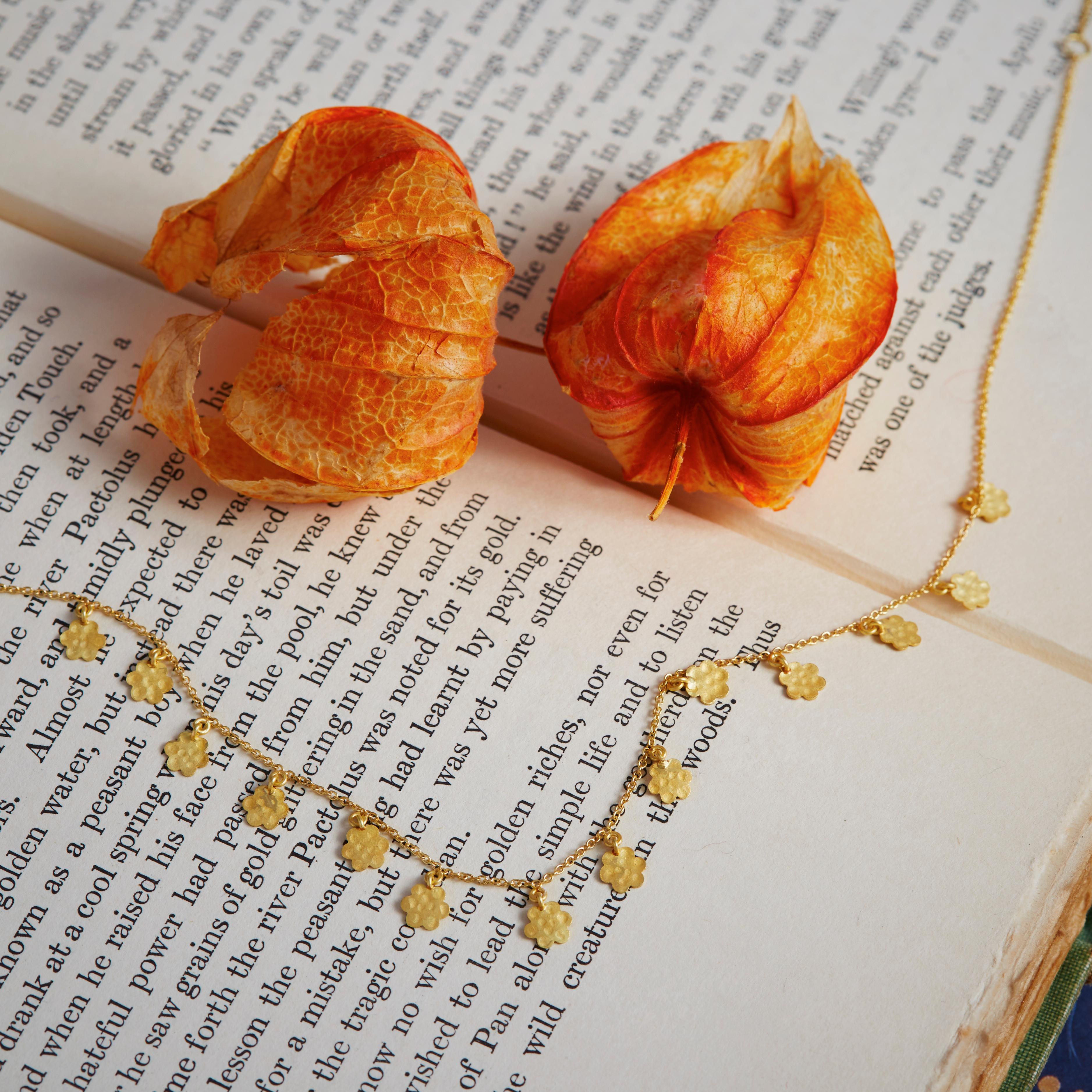 A garland with fourteen, little hammered 18 Karat gold marigolds, hanging along an 17