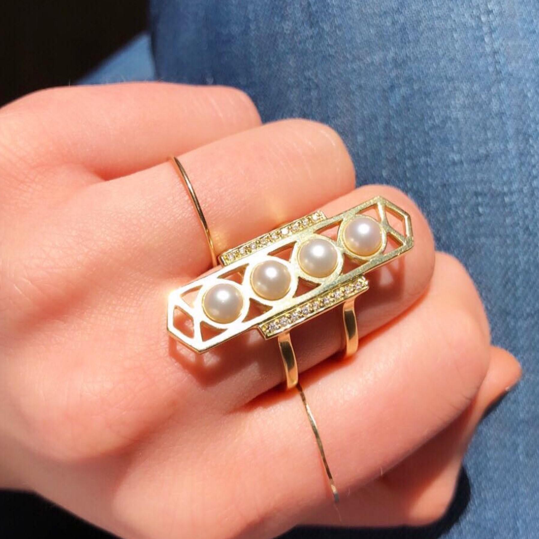 Anello geometrico e drammatico, questo design è una vera e propria dichiarazione.  Di ispirazione classica con una fusione di elementi Art Deco e greci antichi.  Realizzato in oro 18 carati, con perle bianche e due file di diamanti. 
Materiali: Oro