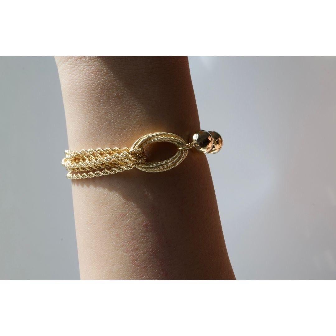 This exquisite 18 karat yellow gold bracelet showcases a stunning combination of textured elements, featuring polished gold beads and intricately woven multi-strand chains. A bold oval centerpiece adds a distinctive touch, blending elegance with