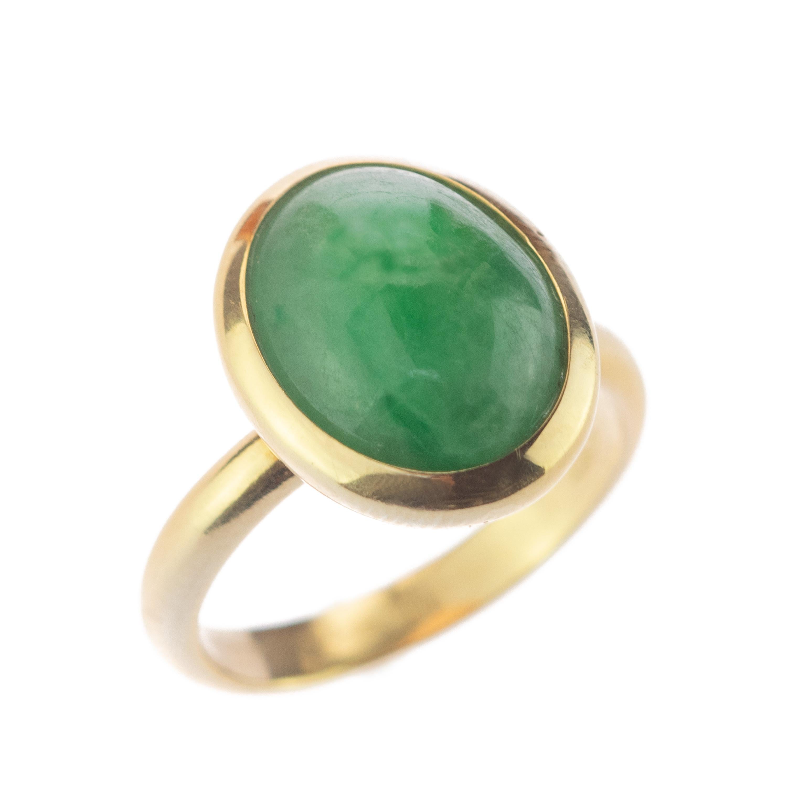 This minimalist design enhances a matte precious natural central 10.5 carats Jade cabochon situated north to south. The 18 karat yellow gold ring highlights the green color and oval shape, surrounding into a glamorous, boho and eccentric touch. Boho