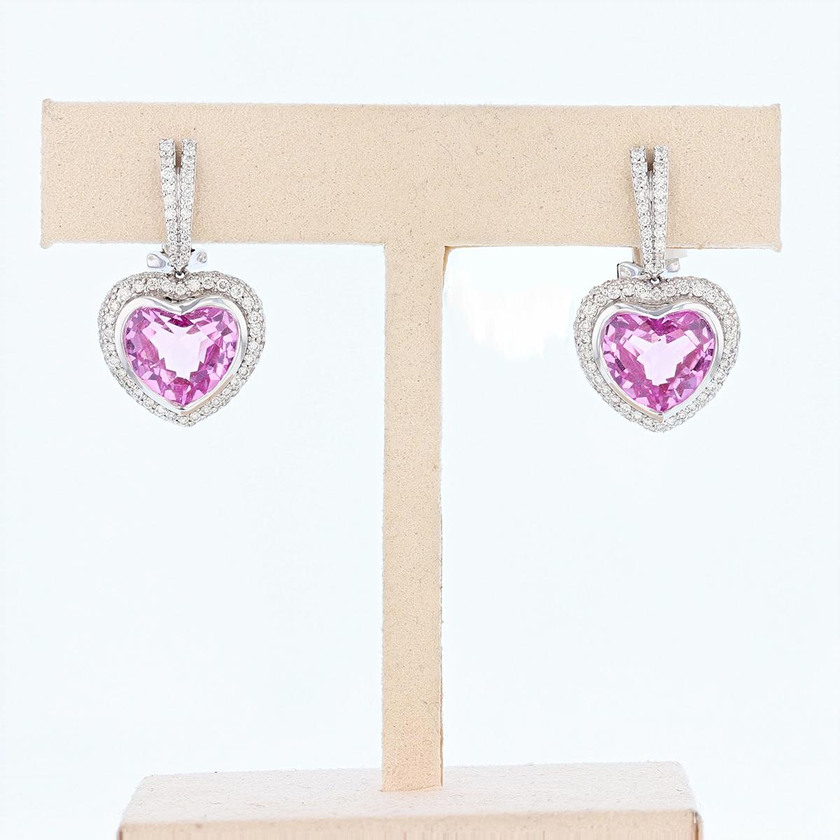 These earrings are made of 18k white gold and features two heart shape pink topaz weighing 13.20ct prong set. The earrings also feature round cut diamonds weighing 1.35cts, prong set.