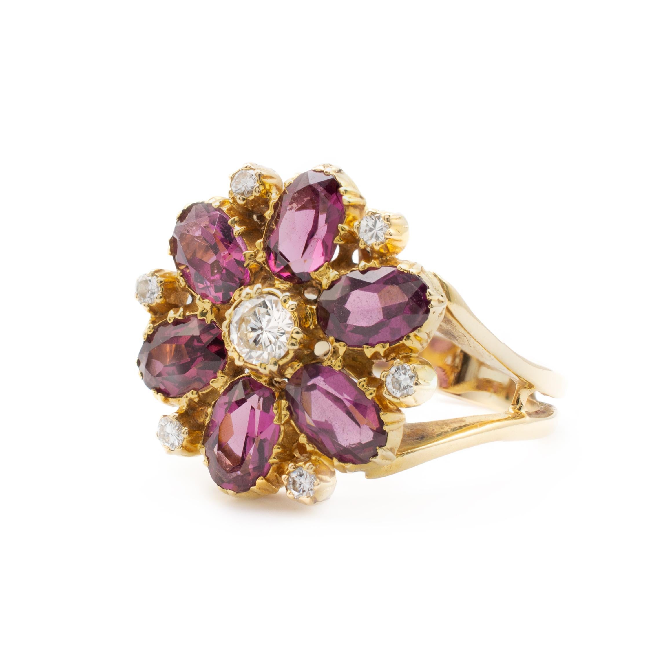 This gorgeous rhodolite garnet and diamond flower cluster cocktail ring crafted is in 18 karat yellow gold and displays a center set diamond with a surround of oval cut rhodolite garnets and smaller diamonds between to form a beautiful flower.