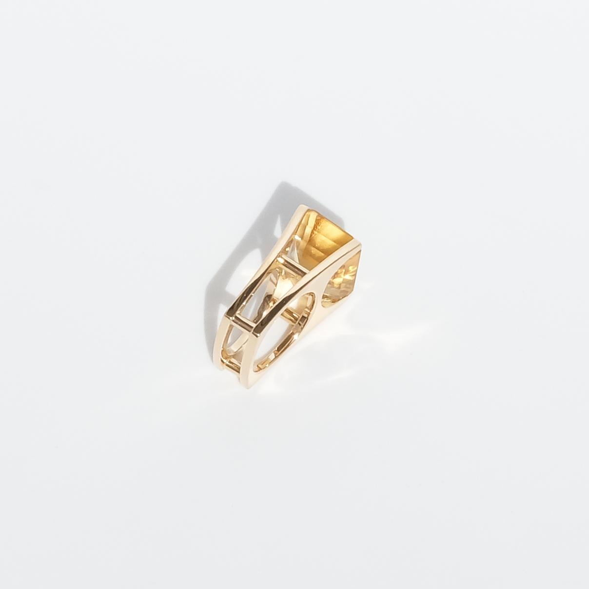 This 18 karat gold ring is has an exquisite design with its high shaped shank and setting. It is adorned with a baguette cut citrine with facets that create this typical hypnotic hall-of-mirrors effect within the stone. The square shaped shank goes