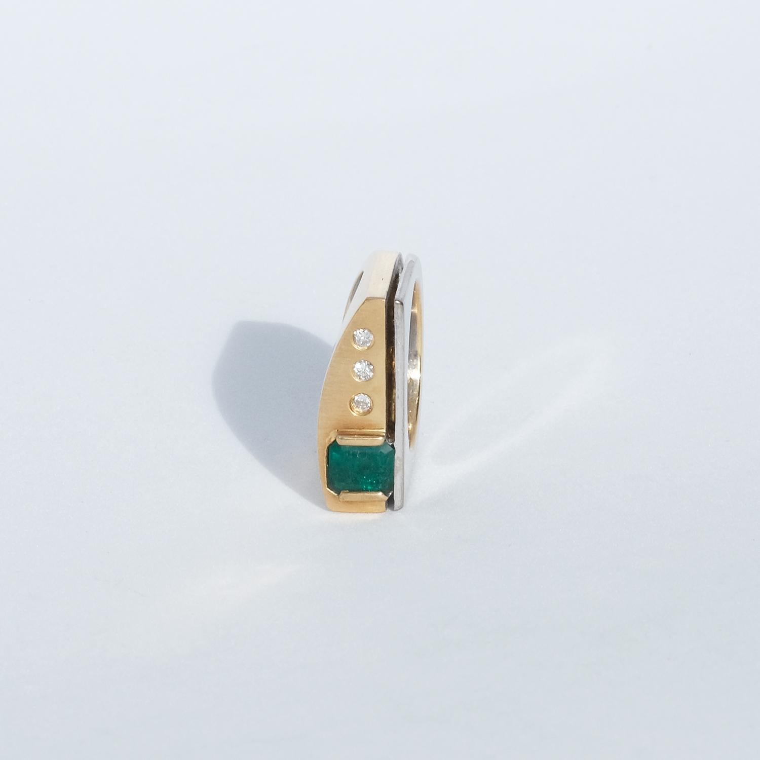 This 18 karat gold and white gold ring has three diamonds and a beautiful faceted emerald. The interesting thing with this ring is the designer's use of both white and yellow gold and the visual effect it creates.

The ring will, depending on your