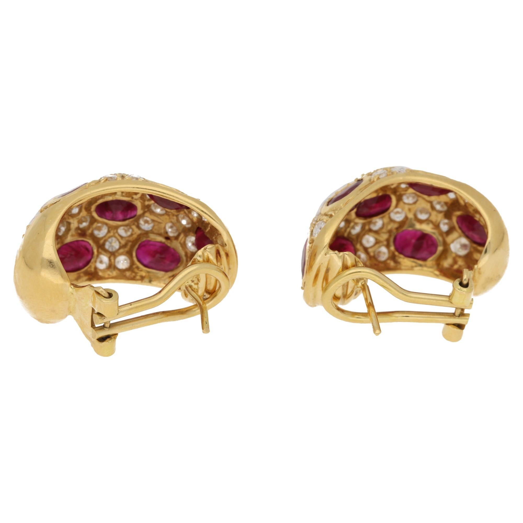 A stylish pair of 1970's ruby and diamond earrings. Each earring is formed of seven oval cut rubies, uniform in colour, in a yellow gold rub over setting.  The rubies are interspersed with thirty round brilliant cut diamonds in a yellow gold