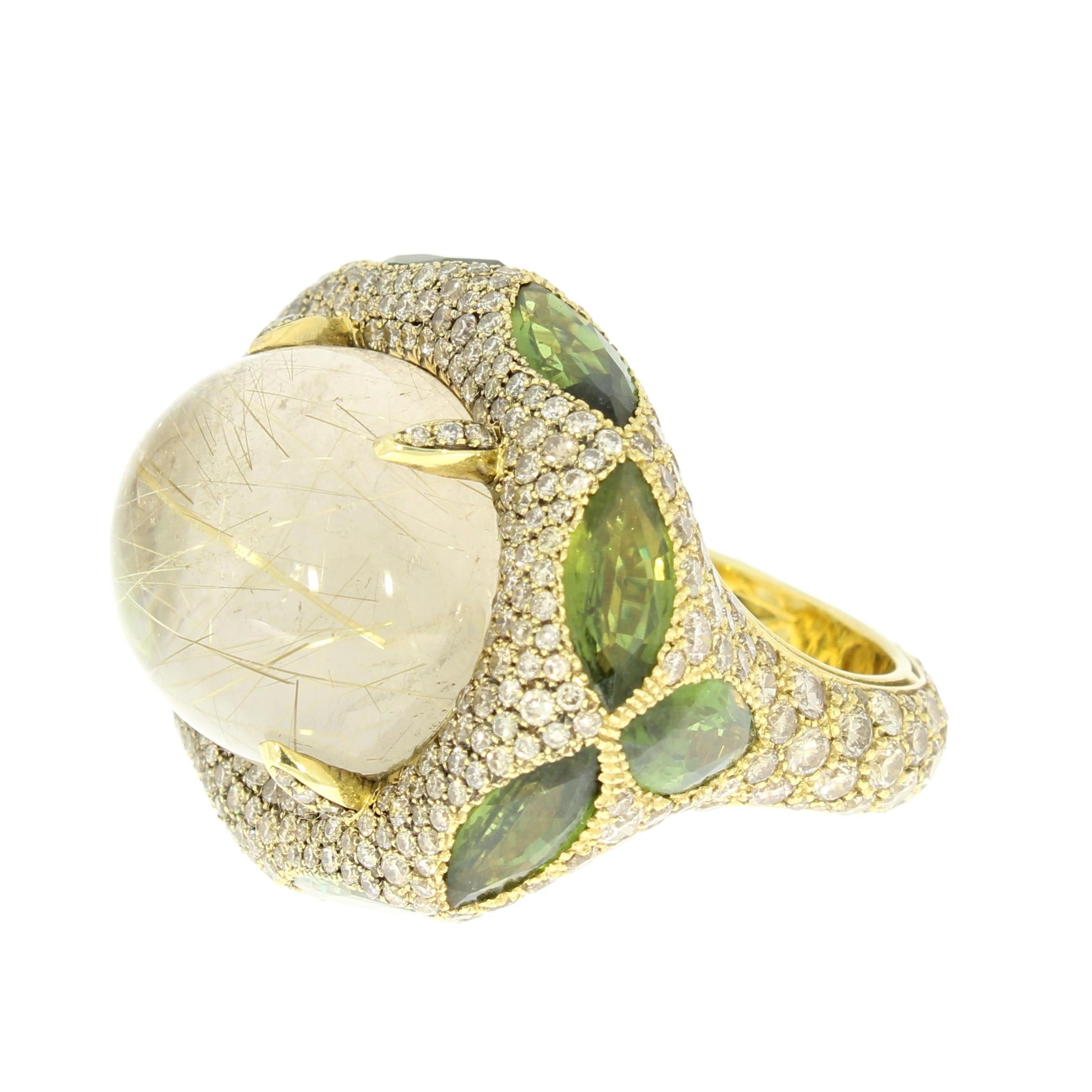 A Cabochon Gold Rutilated Quartz sumptuously nestled among a pave setting of elegant champagne diamonds brilliant cut Diamonds and Marquise cut green sapphires. The Diamonds runs all around the ring. 

18 Karat Yellow Gold (13 grams) 
40 Carats