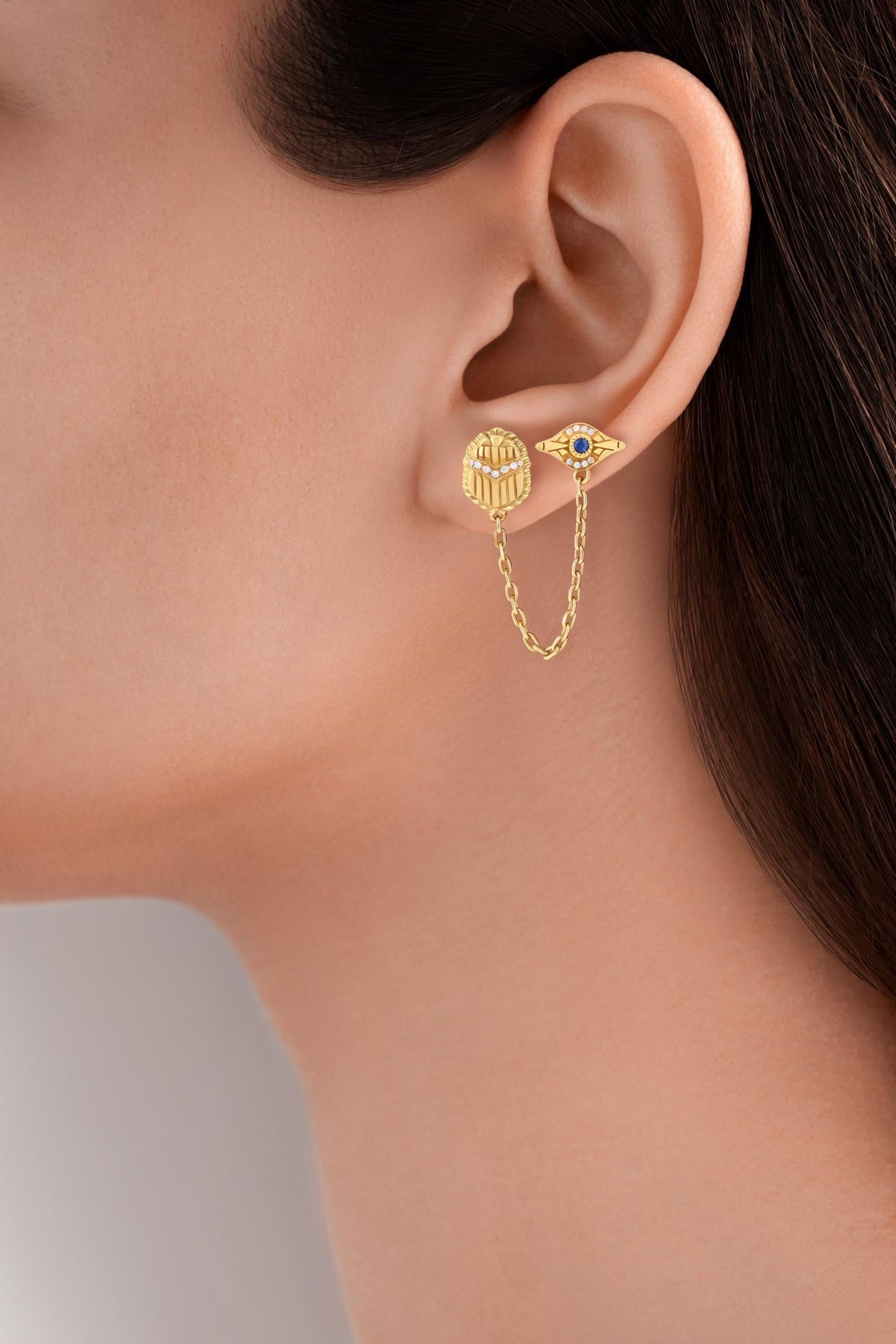 18 Karat Gold, Sapphire and Diamond Eye & Scarab Multi-pierce Chain Stud Earring. Designed to be worn in multiple piercings on one ear. Part of Azza Fahmy's 2020 Egyptomania Collection.

Sapphire: 0.05 carats (Total weight)
Diamond: 0.06 carats