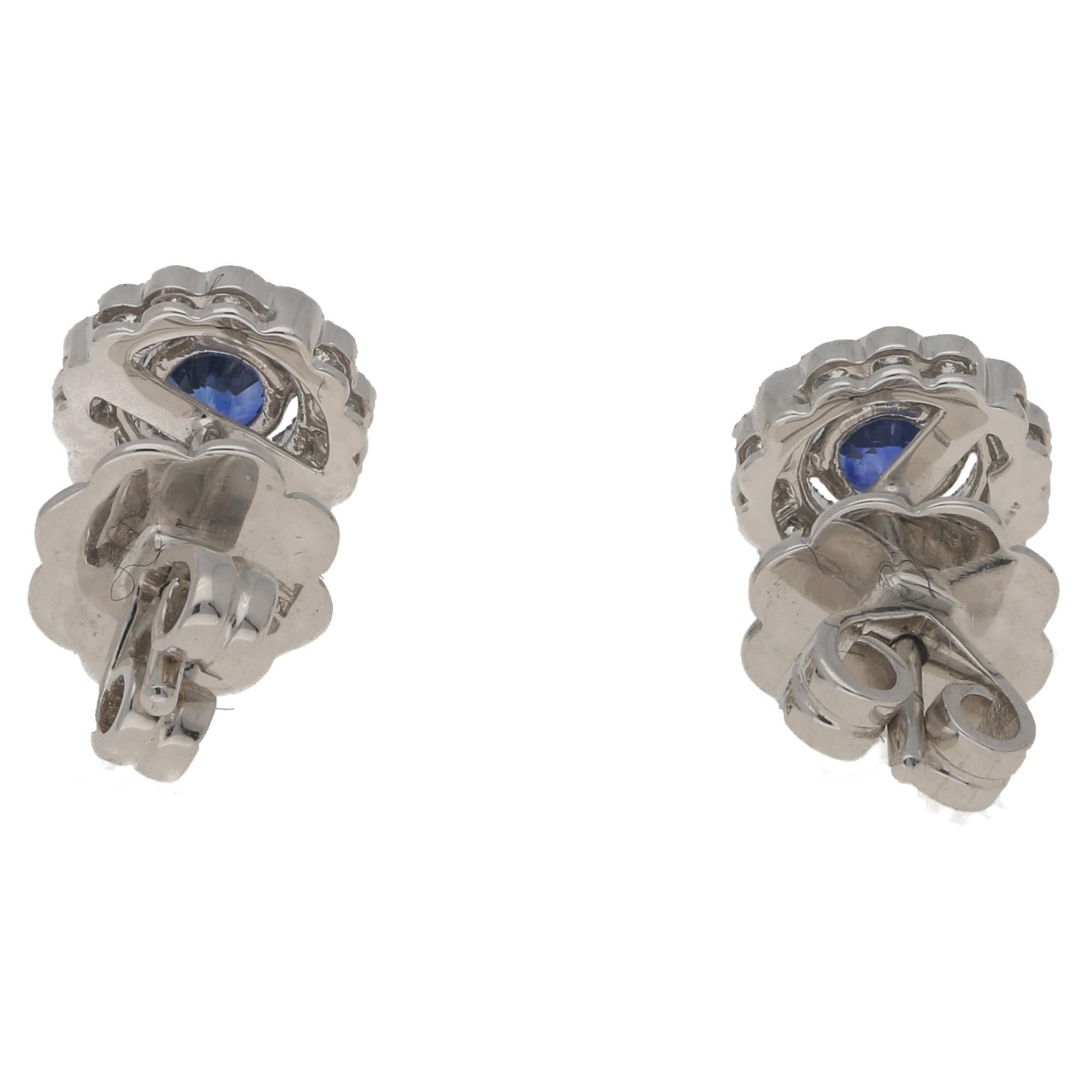 A pair of elegant sapphire and diamond earrings in the classic cluster design, perfect for both day wear and fancy evenings. 

Each earring features a claw-set round-cut deep blue sapphire at the centre with an estimated combined weight of 0.66