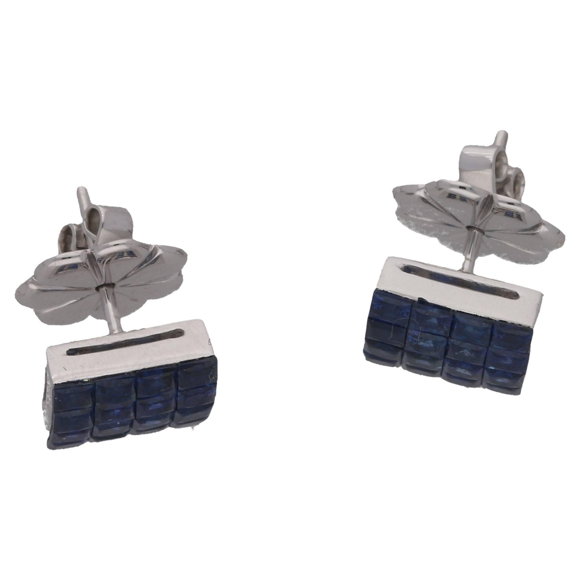 A neat pair of  invisibly set sapphire earrings. The magic is that the stones appear to be suspended with only the outer setting edge visible, in fact each stone is immaculately set. Earrings measure 10mm x 10mm. Total sapphire weight: 4.62 carats.