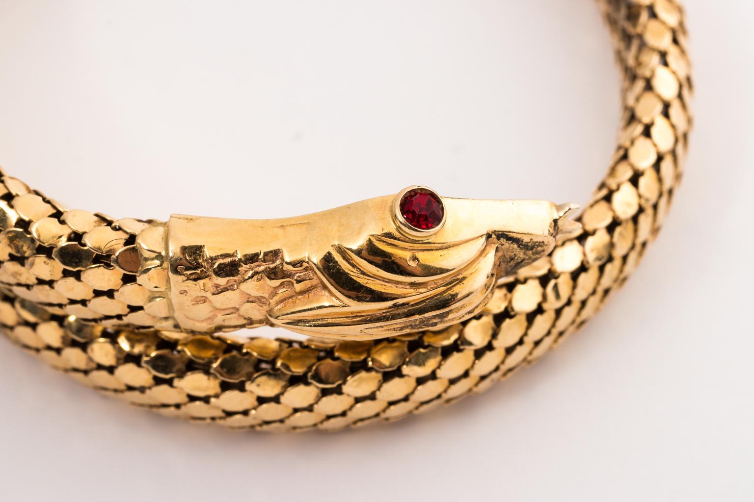 Circa 1950-1960 coiled serpent bracelet in a scale like finish of solid 18 karat gold. The bracelet features a detailed head with Ruby eyes. Made in Italy.
