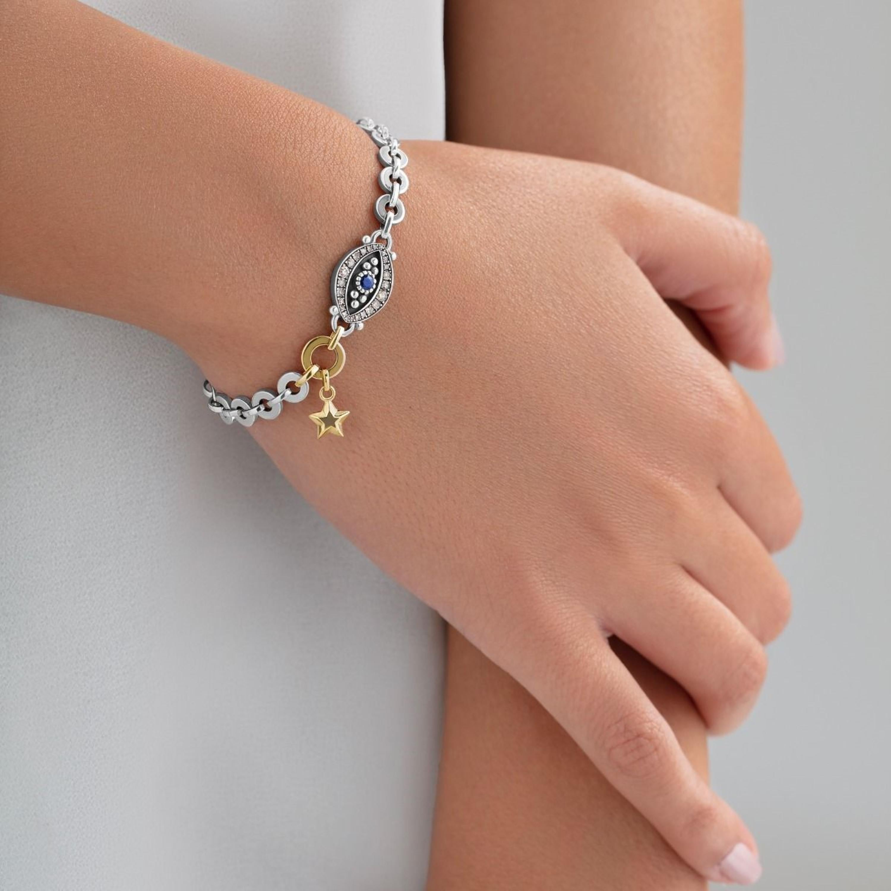 18 Karat Gold and Sterling Silver Eye & Star Bracelet, set with precious stones. 

Featuring a suspended gold star, this 18 Karat Gold and Sterling Silver bracelet carries an eye set with 0.33 carat Champagne Diamonds and 0.20 carat