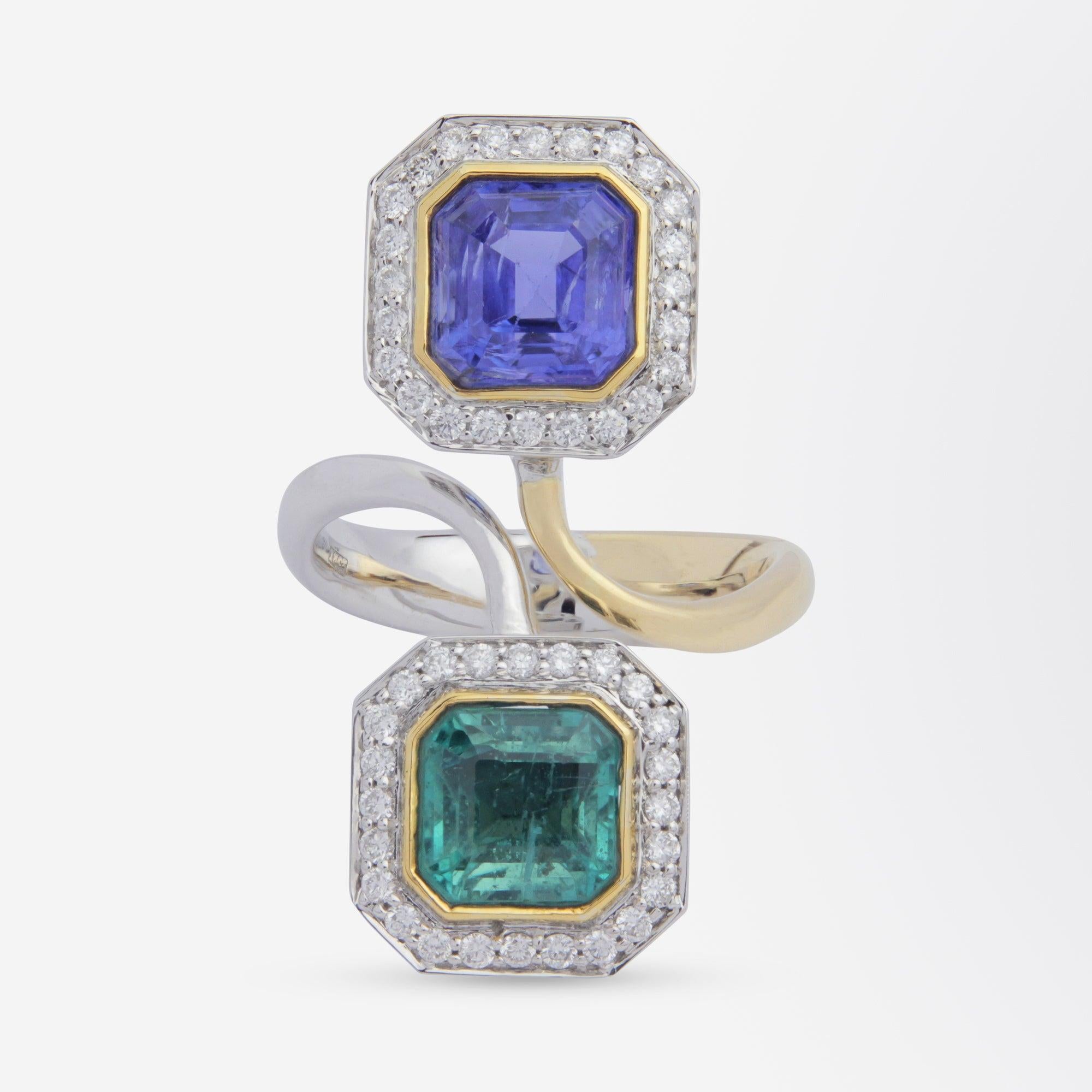A contemporary, handmade, 'toi et moi' ring crafted from two tone 18 karat white gold and set with diamonds, an emerald and a tanzanite. The 50 stone ring features a rub over set emerald and a rub over set tanzanite which are each surrounded by 24