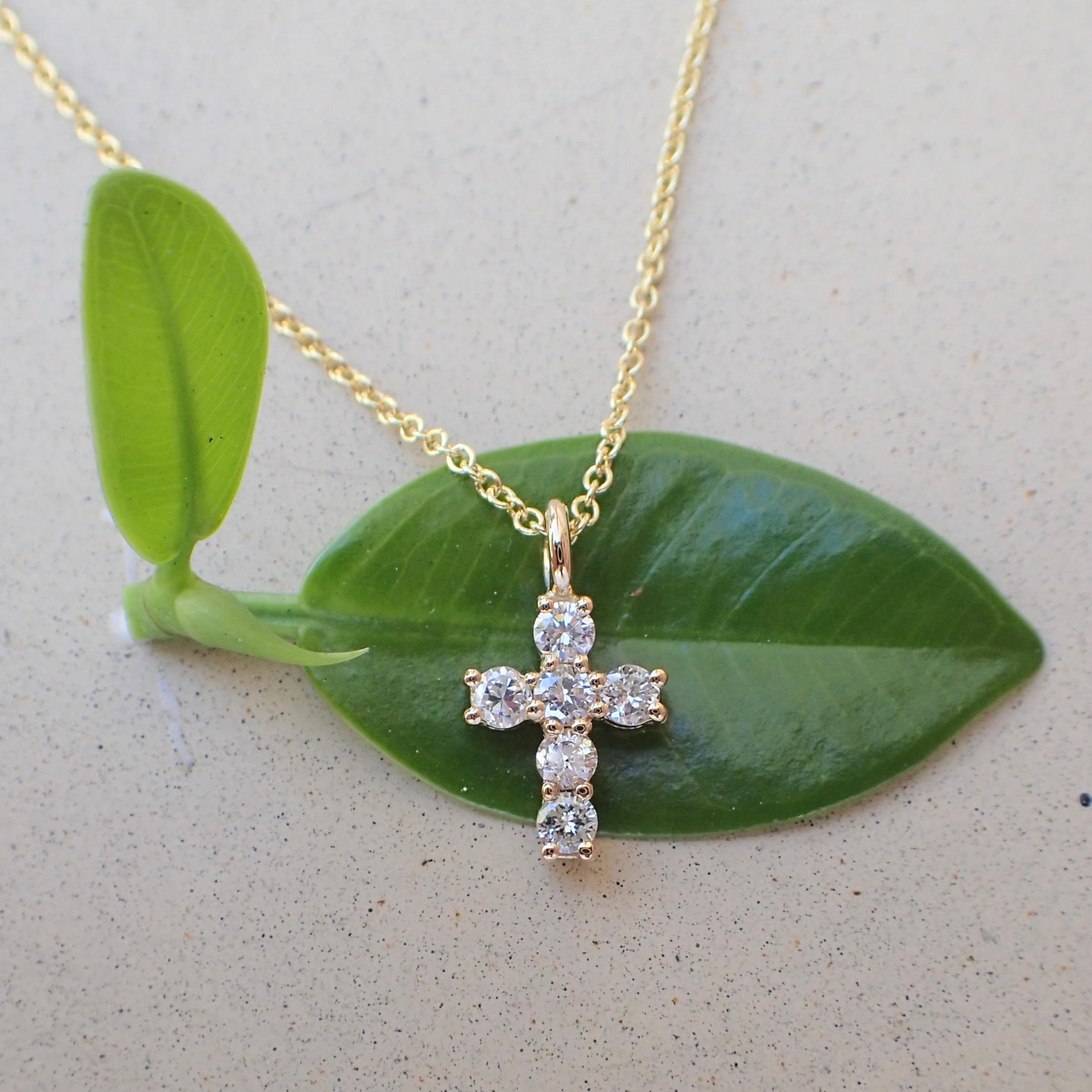 18k yellow gold tiny cross with six (6) Round Brilliant Cut diamonds weighing a total of 0.30 carats with Color Grade G-H and Clarity Grade SI. The cross hangs from a 16
