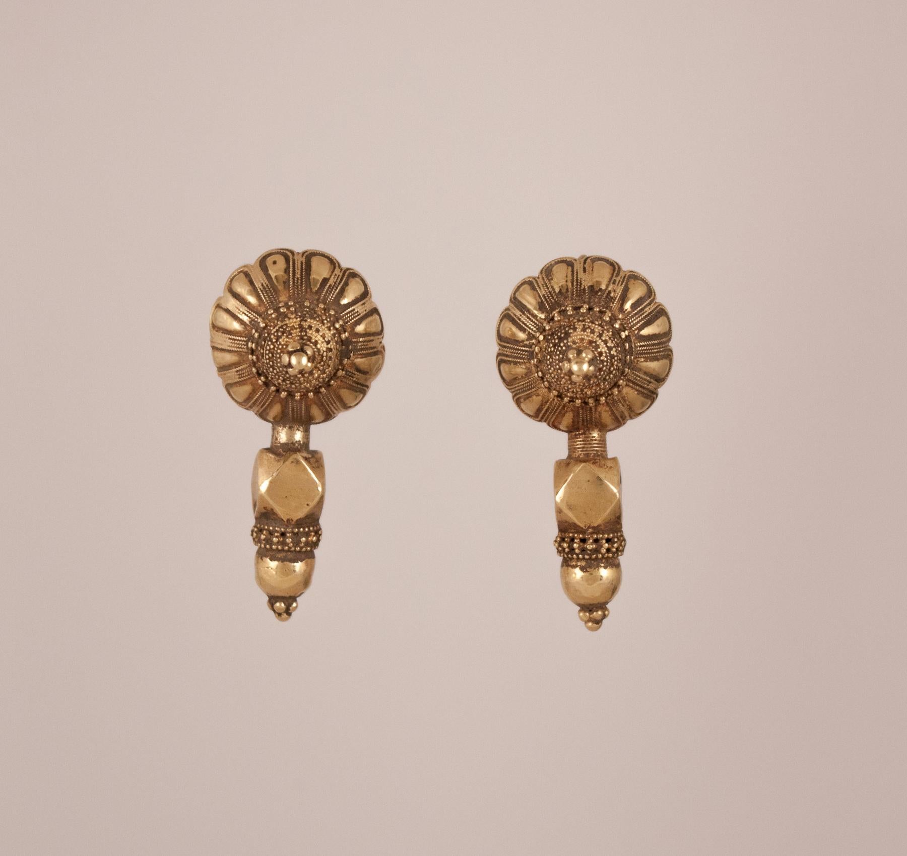 A collector's pair of traditional 18 karat gold fixed wire earrings from Northern India. These circa 1950 ethnic works of art have a wonderfully worn patina and feature hand tooled lotus blossoms, fine granulation work and geometric beads. The wires