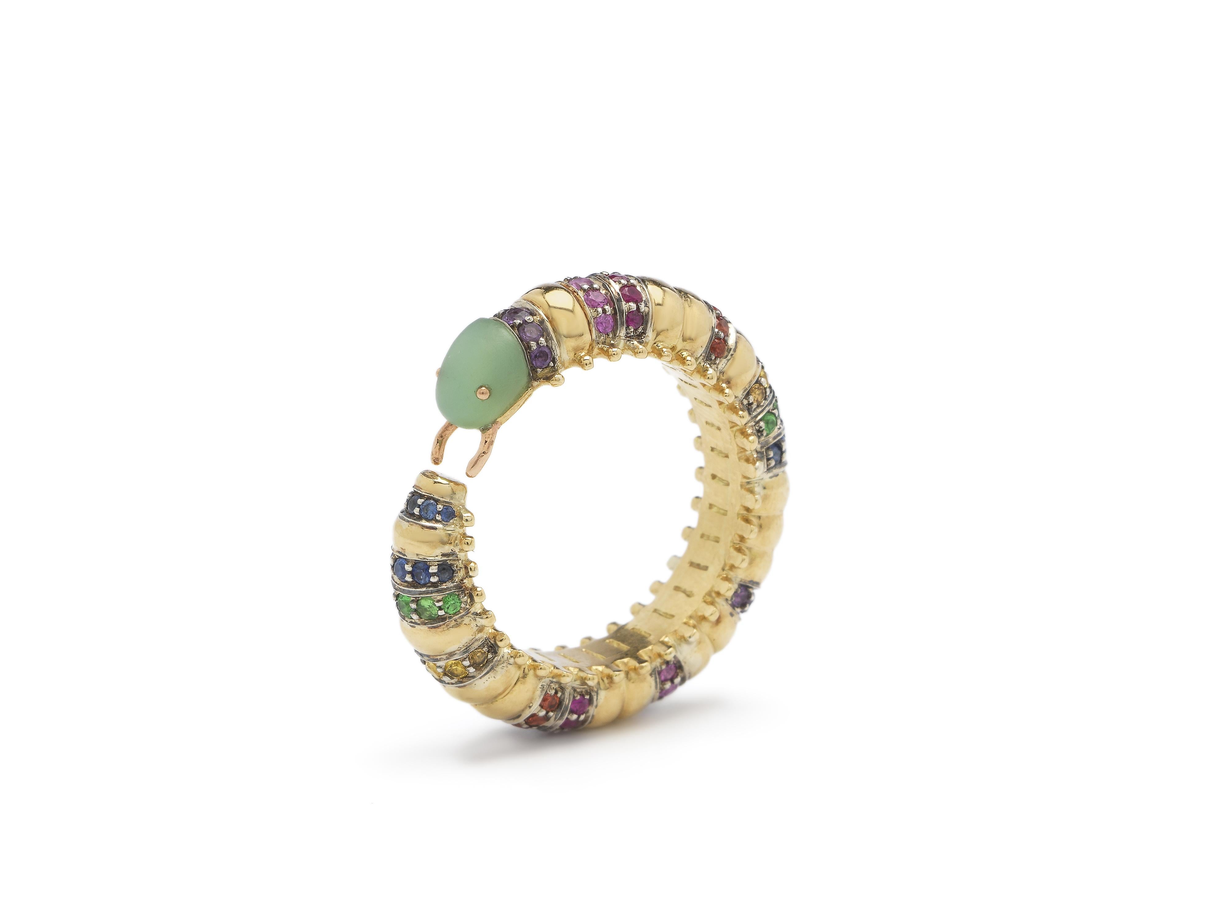 A millipede curves around the finger to form this unique, head-turning eternity ring. The ring is fashioned in 18k yellow gold and sterling silver, with the insect boasting rainbow tones of sapphires that embellish its body, with its head carved in