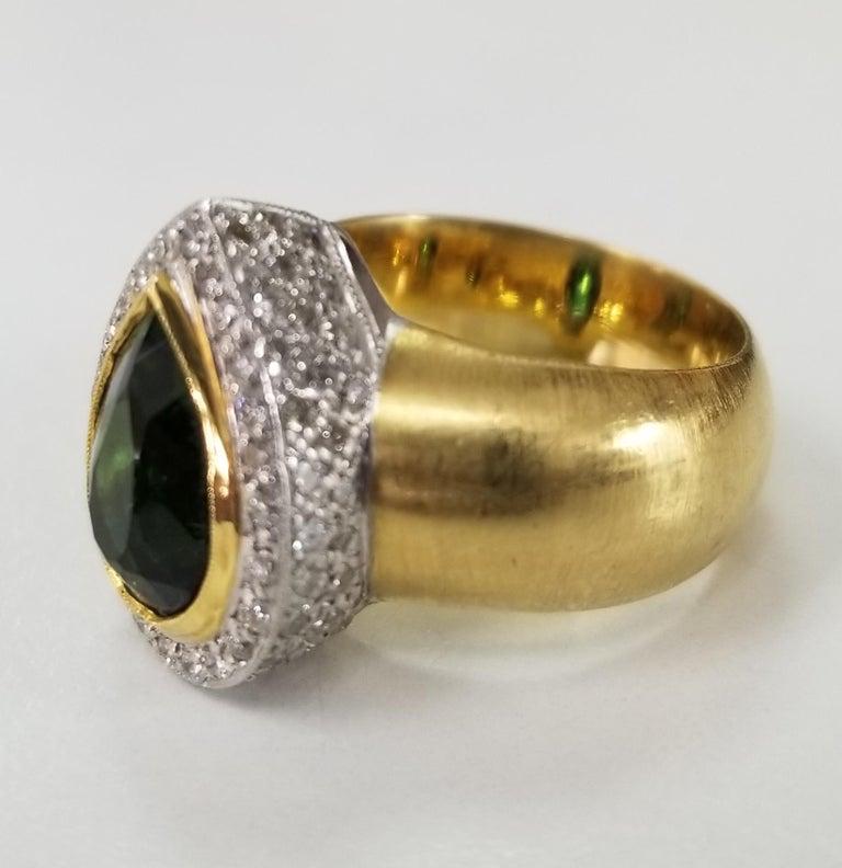 18 karat Green Tourmaline with diamond pave' containing 1 pear shape cut tourmaline of gem quality weighing 3.02cts. surrounded by 85 round full cut diamonds of very fine quality weighing 1.35cts.  This ring is a size 6 but we will size to fit for