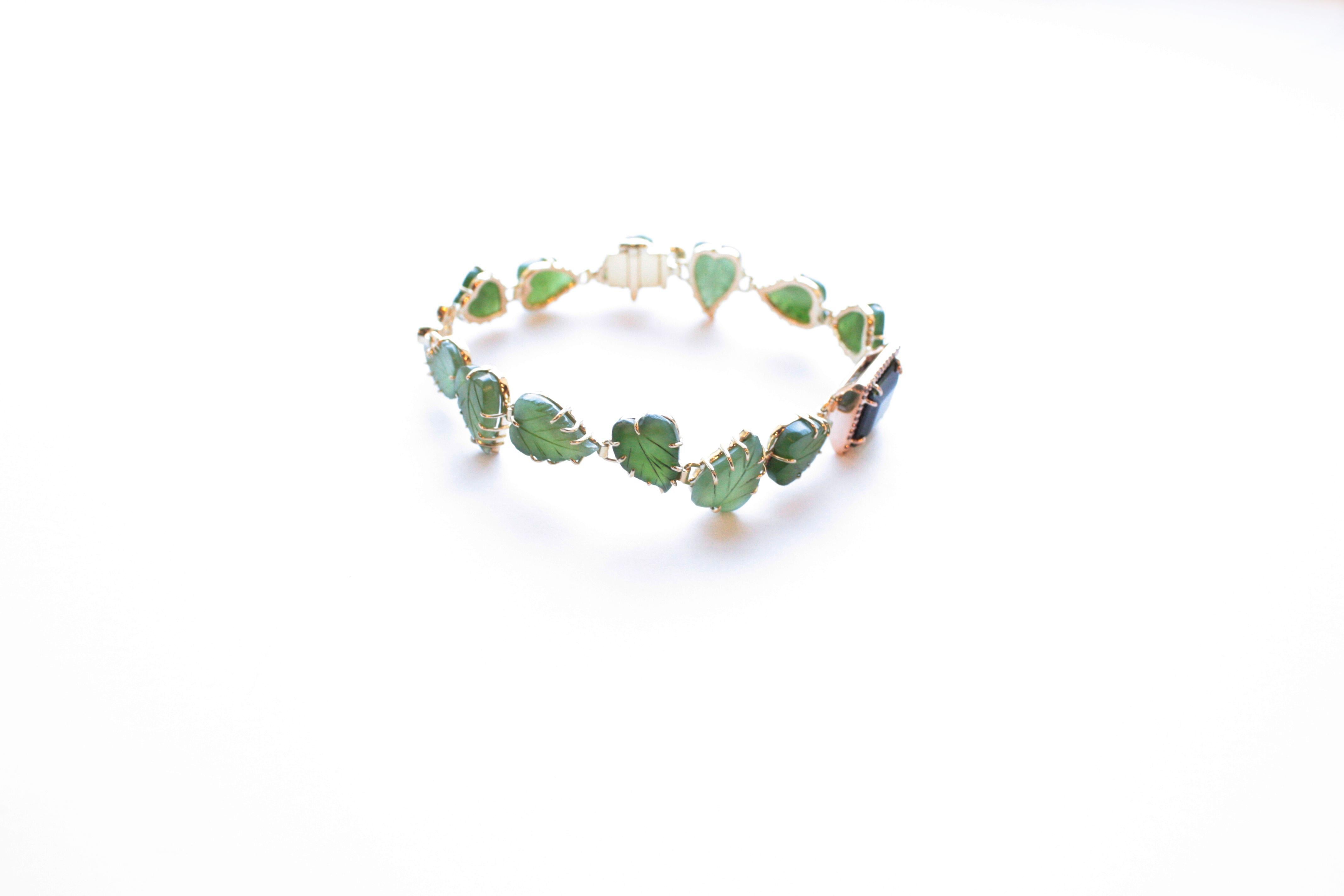 Pomme Bracelet
A thin delicate bracelet fashioned primarily of carved jade leaves.  The distinctive opaque green of the jade is offset by a vividly translucent green tourmaline rimmed with white diamonds in eighteen karat yellow gold at one end, and