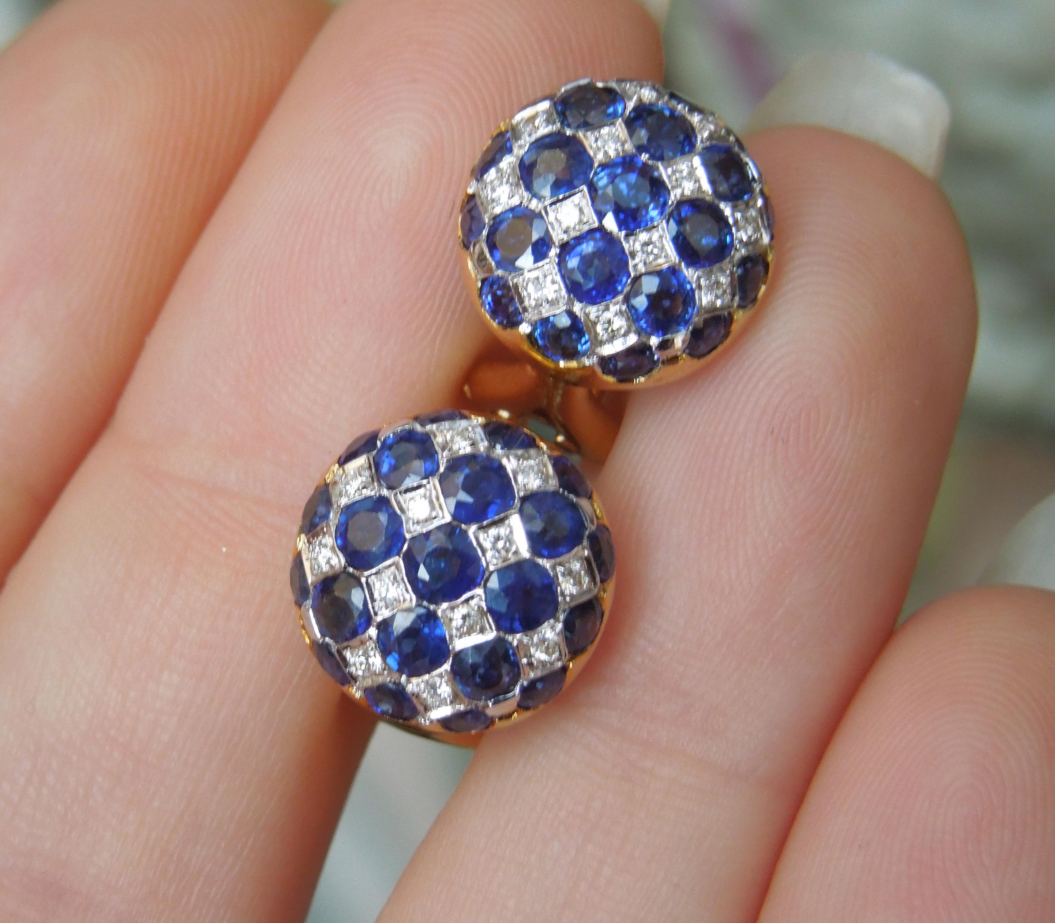 Earrings in a button-shaped design first became popular in the 30s and 40s. These particular earrings are attributed more to the Art Deco era in this symmetrical checkerboard pattern. Featuring 42 Round cut Intense Kashmir Blue Sapphires totaling