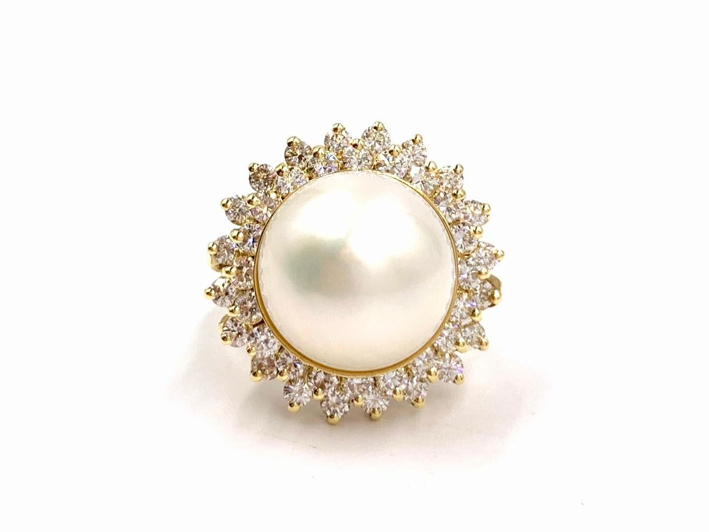 A timeless 18 karat yellow gold cocktail ring featuring a lustrous and smooth 14mm mabe pearl surrounded by 40 diamonds at 1.60 carats total weight. Diamond quality is approximately F-G color, VS2 clarity. The surface of the ivory pearl is free of