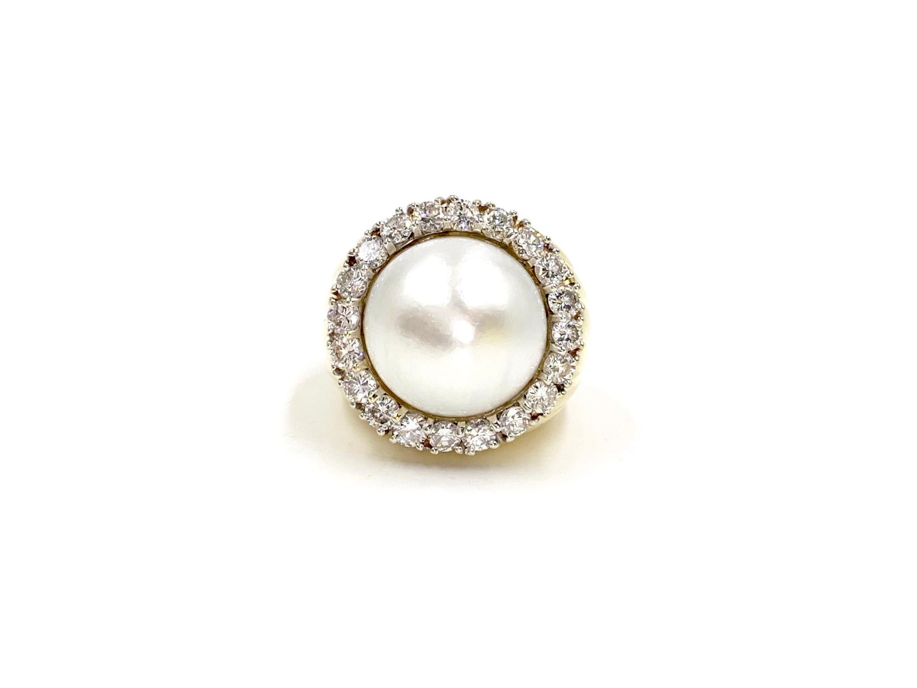 A very well made, heavy and substantial polished 18 karat yellow gold cocktail ring featuring a lustrous cultured white 15mm mabé pearl ring surrounded by 20 round brilliant diamonds at 1.83 carats total weight. Diamond quality is approximately G-H