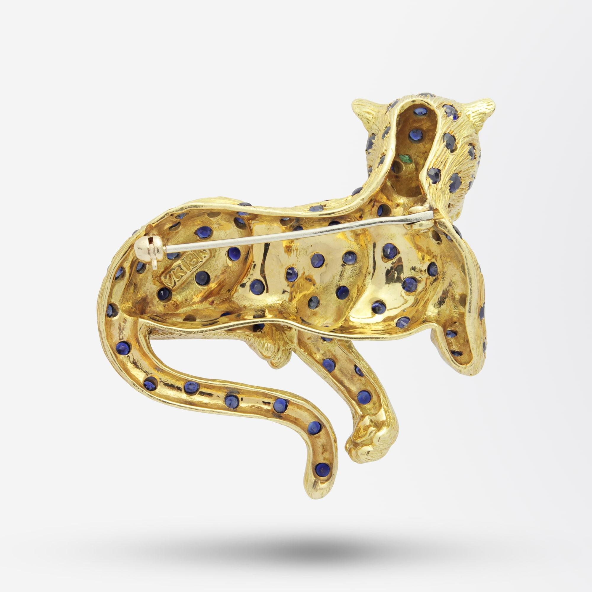 A wonderfully heavy and well made Leopard brooch pin in 18 karat yellow gold in the manner of Cartier. The pin features 69 stones in total and comprises of two marquise emeralds and 67 round sapphires. The textured yellow gold body of the leopard is